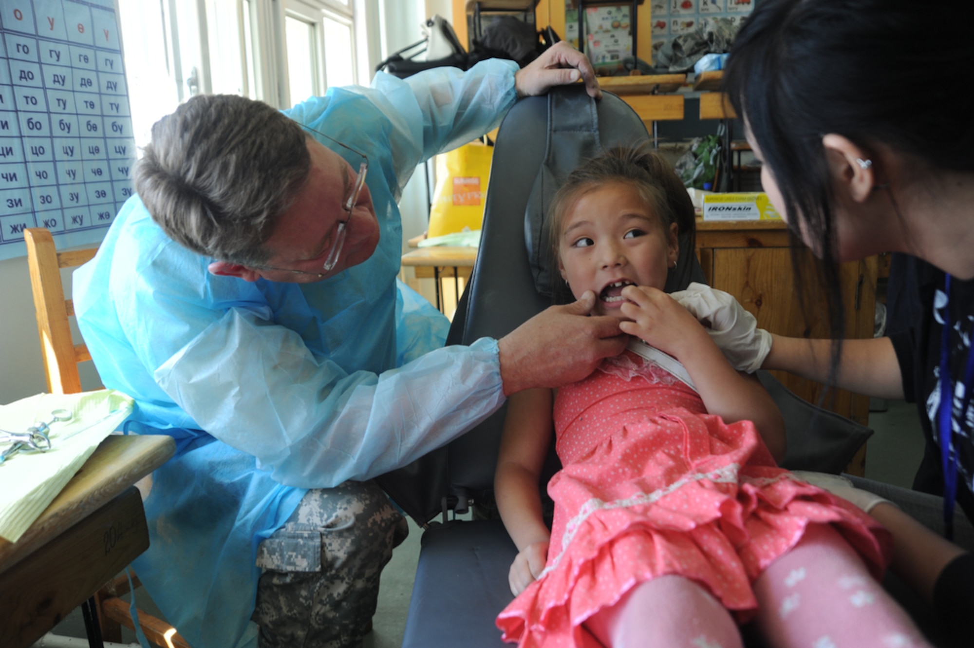 ULAANBAATAR, Mongolia - Lt. Col Jim Arneson, a dentist with the Alaskan Army National Guard looks to see where the tooth hurts in the mouth of a young Mongolian girl with the help of translator, Ms. Oyun Erdone while at the Buynt Uhaa Complex in Ulaanbaatar, Mongolia on Aug. 9 during Khaan Quest 2011, a combined joint-exercise hosted by the Mongolian Armed Forces in partnership with U.S. Pacific Command forces. Medical Civil Action Programs like this enable the countries involved to become familiar with one another in addition to helping the community of the host country.  Khaan Quest officially started July 31 and continues until Aug 12. (U.S.  Air Force photo/Master Sgt. Cohen A. Young)
