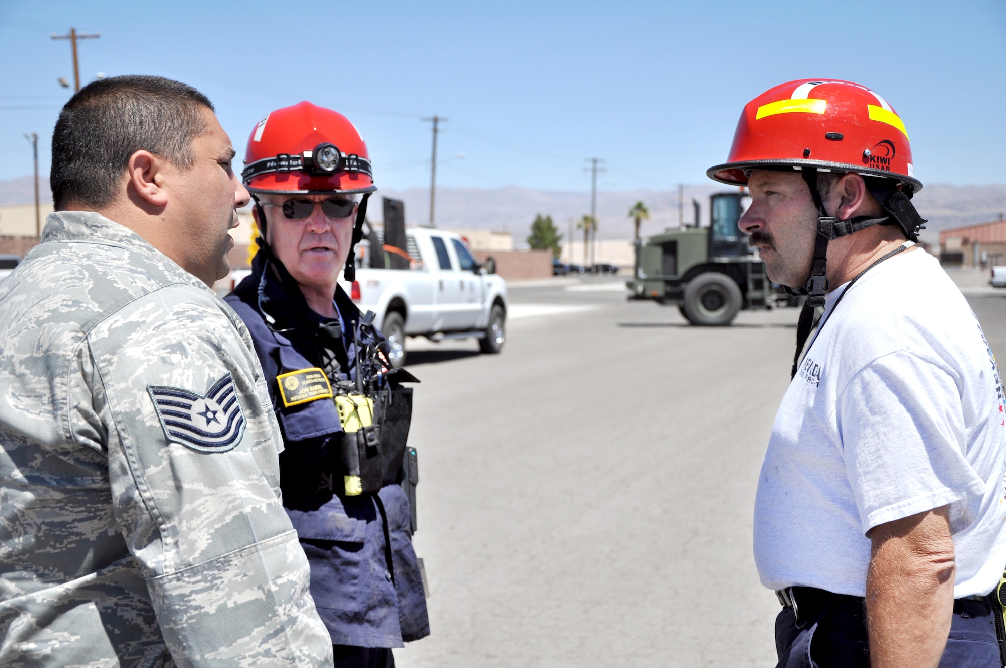 Tech. Sgt. Robert Hrach, 99th Logistics Readiness Squadron deployment training instructor, discusses cargo operations with John Sabol and Chris Thurman, Federal Emergency Management Agency Nevada Urban Search and Rescue Task Force One exercise managers, July 20, 2011, at the cargo marshalling yard at Nellis Air Force Base, Nev. FEMA and the Air Force jointly conducted an exercise to simulate recalling the Nevada Task Force for a disaster or emergency and preparing FEMA personnel and equipment to fly aboard a military aircraft. (U.S. Air Force photo by 2nd Lt. Ken Lustig/Released)
