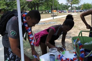Airman 1st Class Max Hodges, 11th Wing Plans and Programs knowledge operations specialist, and Airman 1st Class Bahja Jones, 11th WG Public Affairs specialist, fill out raffle tickets at the Feds Feed Families Pool Party on Aug. 6 at the Base Pool here. The party was set up to collect non-perishable food and other items, and distribute them to food banks in the National Capital Region. (U.S. Air Force photo by Staff Sgt. Kris Levasseur)