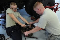 Staff Sgt. Jeffery Griffin assists Airman1st Class Matthew Fincher as he removes the bolts off of a wheel hub Aug. 9 at the vehicle maintenance shop at Joint Base Charleston - Air Base. Griffin and Fincher are from the 628th Logistics Readiness Squadron.  (U.S. Air Force photo/ Staff Sgt. Nicole Mickle)