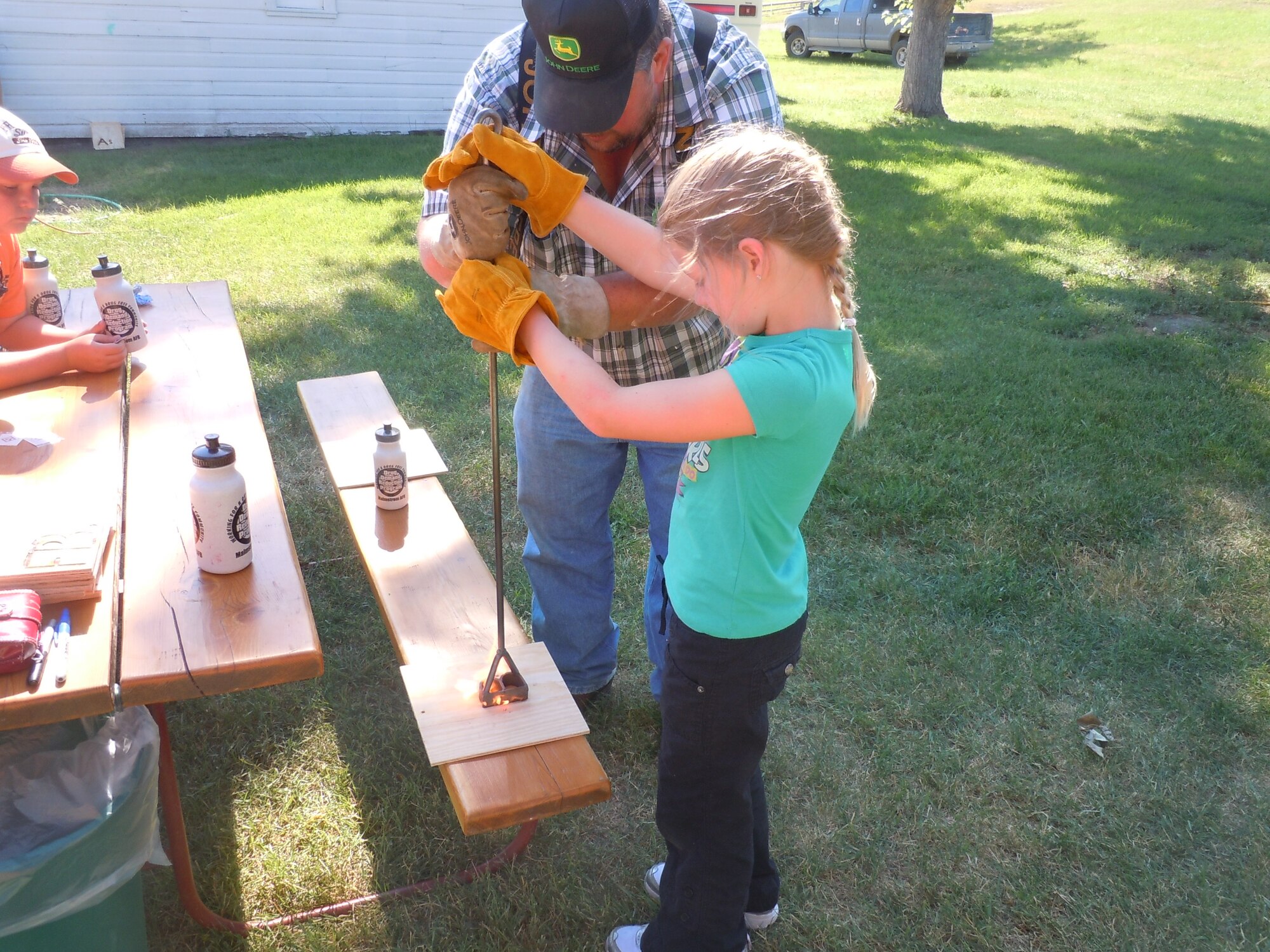 Brianna Edwards, 9, gets some help from a Montana Farm Bureau Federation volunteer making a souvenir brand to remember her "Montana Cowboy Culture" camp experience.  (Courtesy Photo)