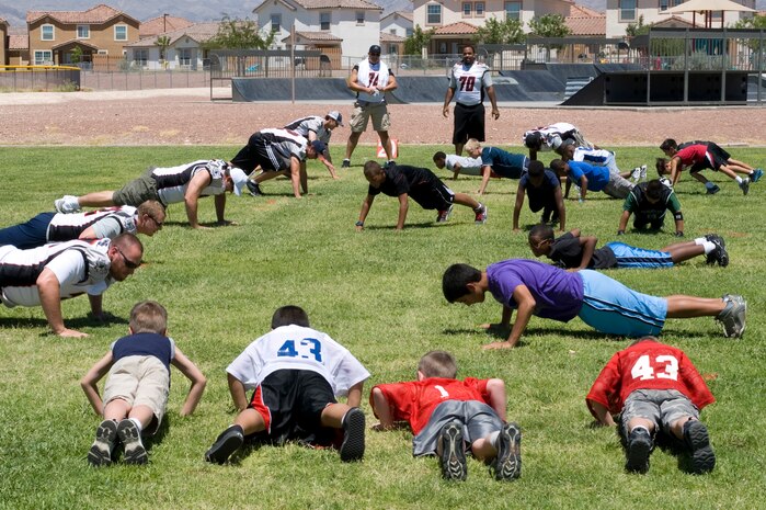 Las Vegas Locomotives football players and Nellis Air Force Base children do push-ups Aug. 5, 2011, at Nellis Air Force Base, Nev. The Las Vegas Locos football players, dancers and coaches toured Nellis AFB and spent time at the Nellis Youth Center teaching the children the fundamentals of football, dancing and sportsmanship. (U.S. Air Force photo by Airman 1st Class Matthew Lancaster/Released)
