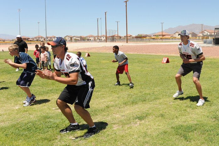 Eric Peterman and Chad Friehauf, Las Vegas Locomotives football players, lead children from the Nellis Youth Center through a series of football drills Aug. 5, 2011, at Nellis Air Force Base, Nev.  The Las Vegas Locos football players, dancers and coaches toured Nellis AFB and spent time at the Nellis Youth Center teaching the children the fundamentals of football, dancing and sportsmanship. (U.S. Air Force photo by Staff Sgt. Taylor Worley/ Released)