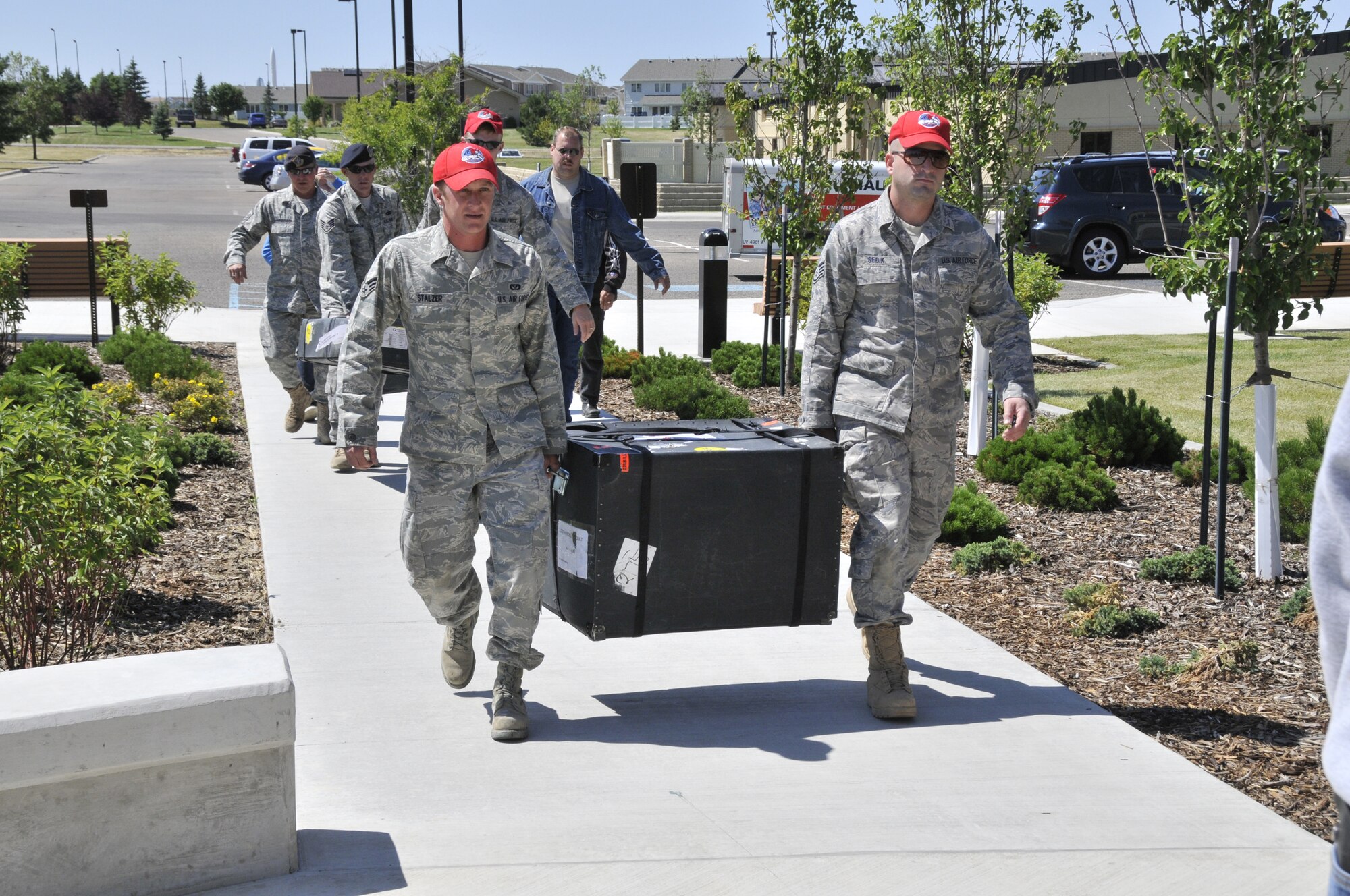 Senior Airman Joseph Stalzer and Staff Sgt. Alexander Sebik, both pavement and equipment apprentices with the 819th RED HORSE Squadron, with other Malmstrom security forces members, transport the Lost Heroes Art Quilt into the Grizzly Bend Club for a tribute ceremony and brief exhibit.  (U.S. Air Force photo/John Turner)