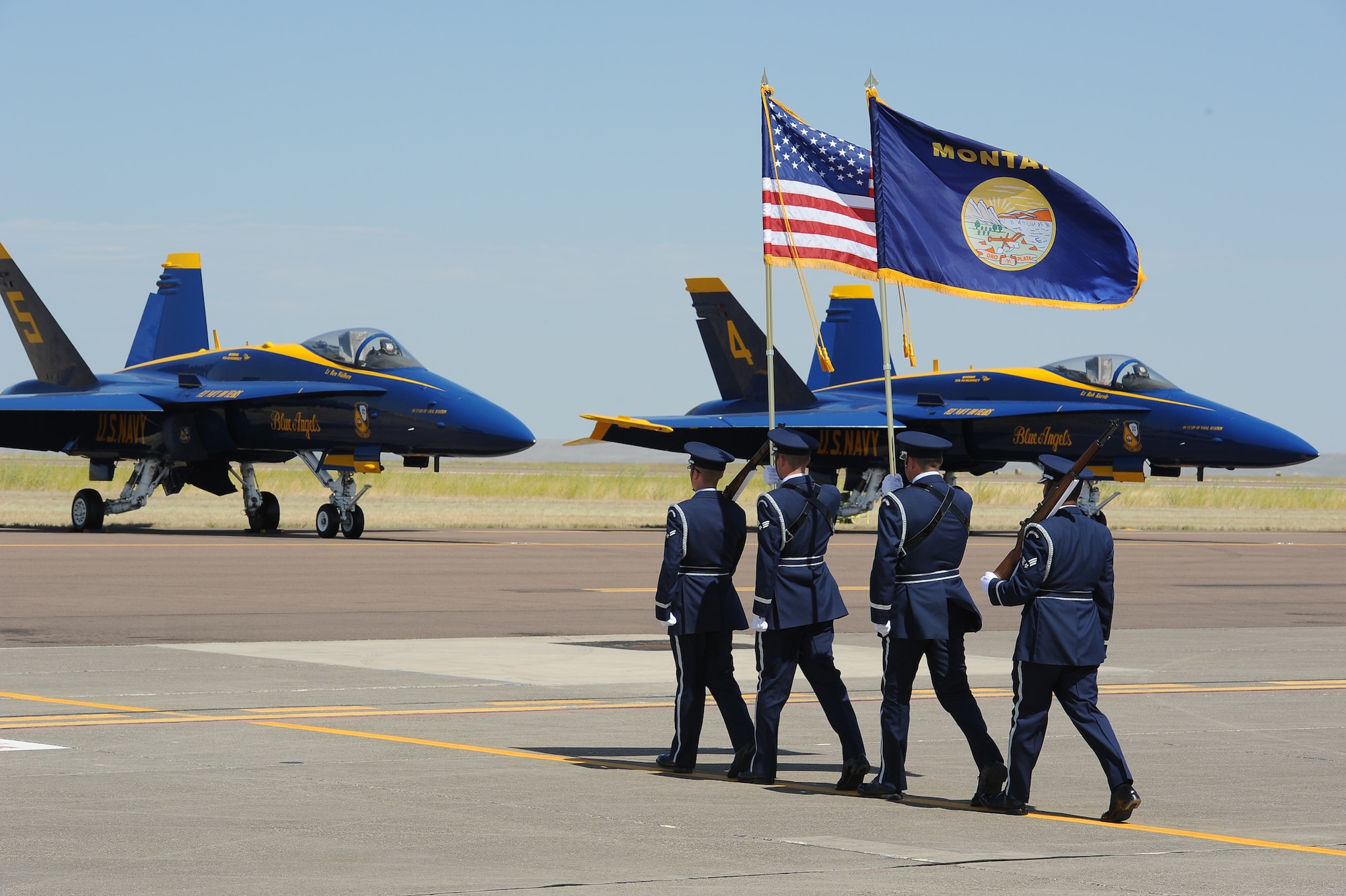 A joint Honor Guard, comprised of Malmstrom Air Force Base and Montana Air National Guard members, march in front of the U.S. Navy's Blue Angel F/A-18 Hornets preparing to post the colors for the national anthem.  (U.S. Air Force photo/Beau Wade)