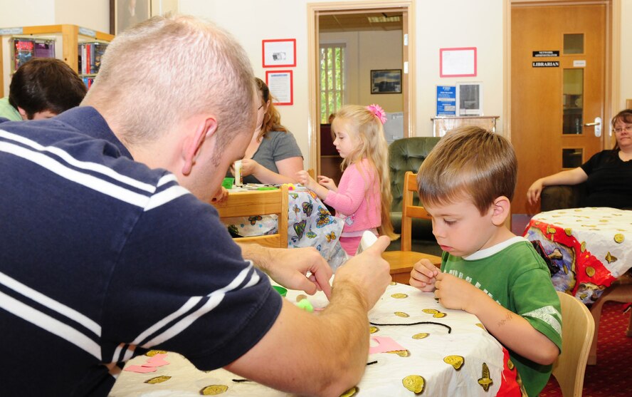 RAF MILDENHALL, England -- Staff Sgt. Mike Smith, left, 100th Operations Support Squadron, glues pieces of paper to help his son Ethan, 4, make a 'mouse' during craft activities at the base library here Aug. 10, 2011. Children had the opportunity to make crafts and listen to a story at the event, held every Wednesday from 10:30 to 11:15 a.m. (U.S. Air Force photo/Karen Abeyasekere)