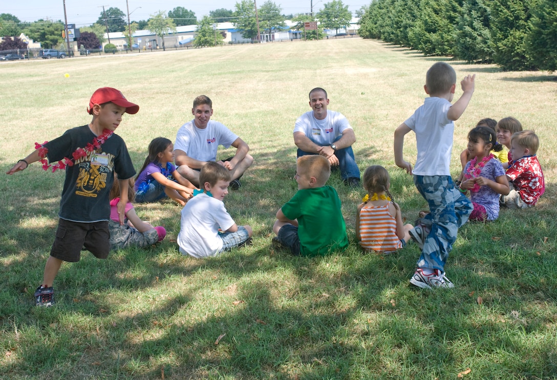 Chapel I Vacation Bible School volunteers, Airman 1st Class Norbert Dudzic, (left), 744th Communications Squadron cable maintenance apprentice, and Airman 1st Class Travis Yannell, 744th  CS cable maintenance apprentice observe as Alex Guinn, 6, races against Alejandro Camacho, 5, to an empty space within the circle during a game of Duck, Duck, Goose Aug. 1. Alex is the son of Master Sgt. Arthur Guinn, 89th Communications Squadron maintenance supervisor.  Alejandro is the son of Army Staff Sgt. Miguel Camacho, U.S. Army Priority Transport Command flight engineer. (Photo by Bobby Jones)
