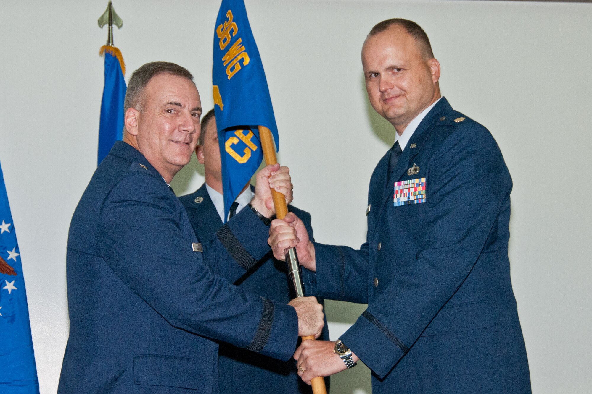 Brig. Gen. John Doucette (left), 36th Wing commander, passes the 36th Comptroller Squadron guidon to Maj. Alan Copeland, newly appointed 36 CPTS commander, during a change of command ceremony at the Sunrise Conference Center here Aug. 9.(U.S. Air Force photo by Staff Sgt. Alexandre Montes)