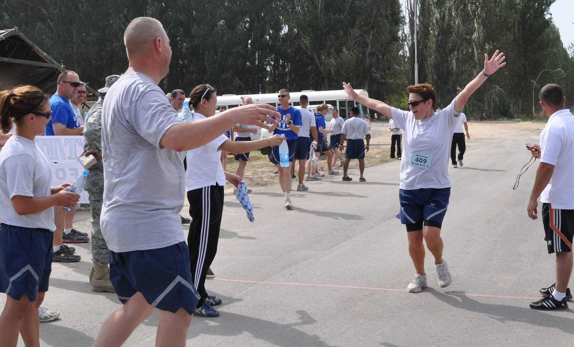 The crowd cheers as Senior Master Sgt. Lanita Vargas crosses the finish line during a half-marathon race at the Transit Center at Manas, Kyrgyzstan, Aug. 8. Vargas, the 376th Expeditionary Force Support Squadron personnel support for contingency operations superintendant, captured first place in her age category. She is deployed here from Joint Base Pearl Harbor-Hickam, Hawaii. (U.S. Air Force photo/Senior Airman Chelsea Zalduondo)