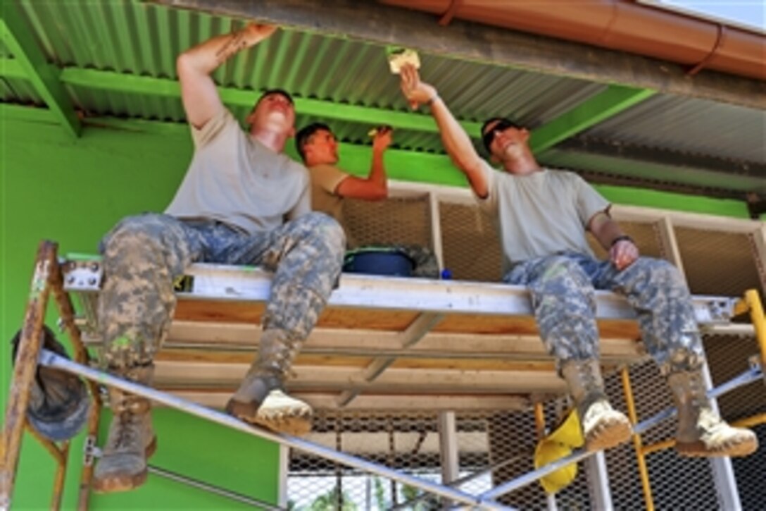 U.S. Army Spcs. Chase Cummings, Mike Dodge and Bob O’Grady apply fresh paint to the eaves of the Pater van der Pluym School in Brownsweg, Suriname, Aug. 6, 2011. The soldiers are assigned to the South Dakota National Guard's 155th Engineering Company.