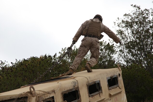 Cpl. Raul C. Acosta, the lead wrecker instructor, Motor Transport Maintenance Company, 1st Maintenance Battalion, Combat Logistics Regiment 15, 1st Marine Logistics Group, connects chains to an overturned Mine-Resistant Ambush Protected vehicle, during a vehicle recovery exercise at Camp Pendleton, Calif., Aug. 10.