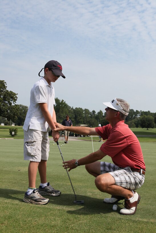 Rick Kunkle, a professional golfer and manager of Marine Corps Base Camp Lejeune’s Paradise Point Golf Course, corrects a junior golfer’s grip during the 3-Day Junior Golf Clinic offered to children ages 8 through 18 at the Paradise Point Golf Course aboard MCB Camp Lejeune, Aug. 10. During the clinic, junior golfers learned proper stances, grips and swings as well as courtesies shown to the field and other players.