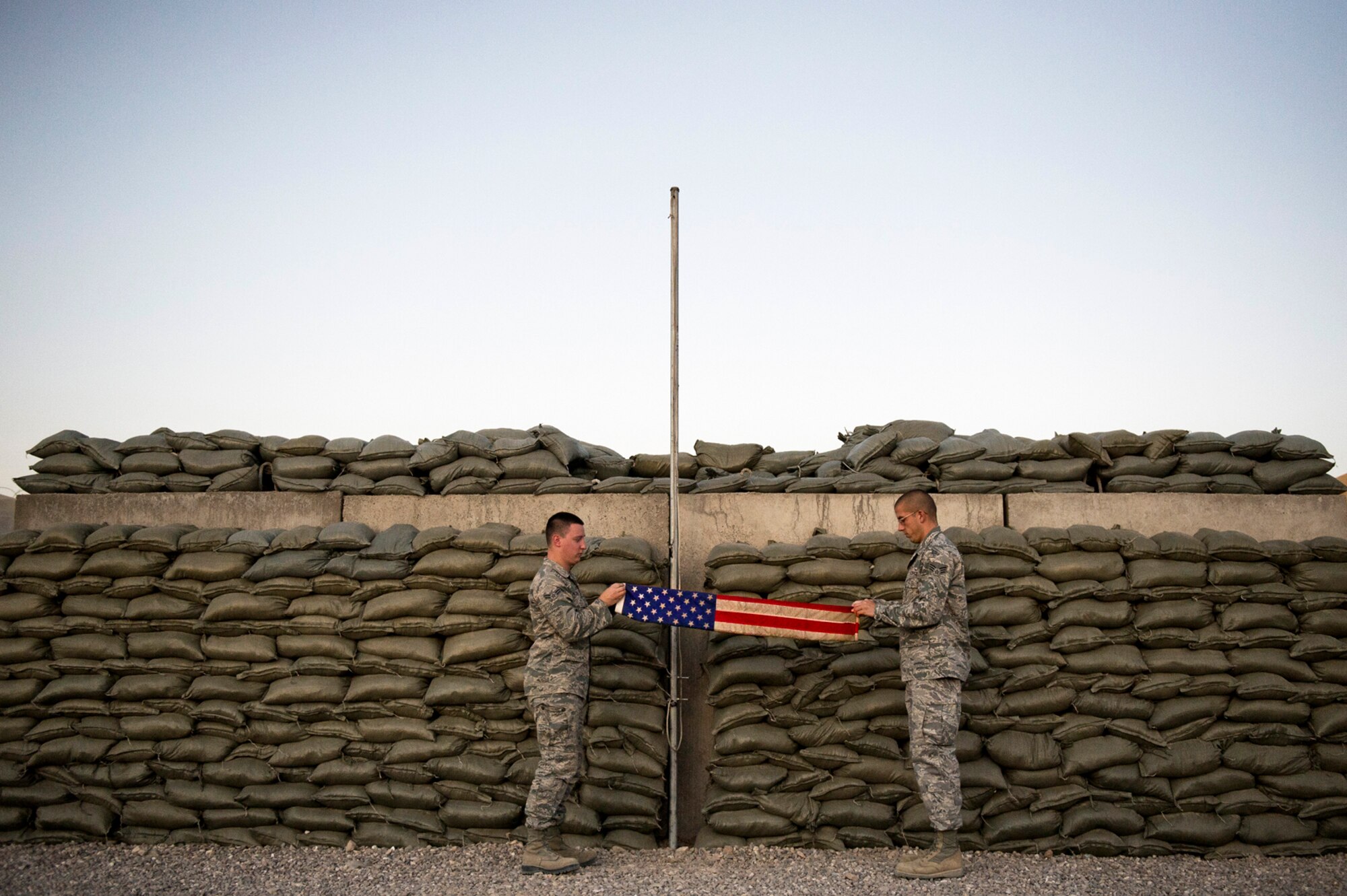 Airman 1st Class Arron Fairfax (left) and Senior Airman Ryan Adkins fold the flag during the daily retreat ceremony at Camp Etchberger, Afghanistan. Airmen at the camp perform reveille and retreat ceremonies everyday during their deployment. Both Airmen are part of Detachment 1, 73rd Expeditionary Air Control Squadron. (U.S. Air Force Photo/Master Sgt. Jeffrey Allen)