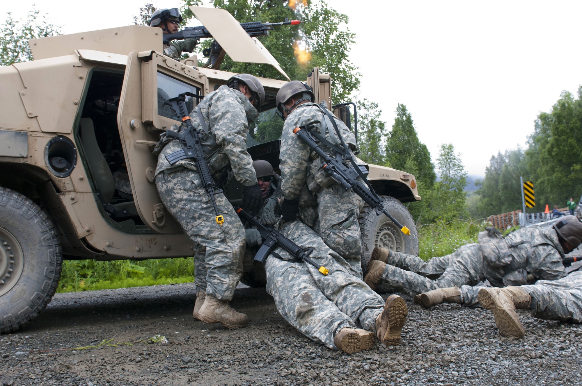 Soldiers from B Company, 1st Battalion-143rd Infantry Regiment (Airborne), load Spc. Coleman Wenke, rifl eman, into a Humvee after he was ‘wounded’ during a simulated near-ambush attack while Spc. David Tunutmoak, machine gunner, provides suppres-
sive fi re. The unit conducted a three-week pre-deployment training and validation exercise in preparation for their deployment to Afghanistan this fall. Wenke is from Anchorage and Tunutmoak is from Scammon Bay. (U.S. Army photo/Staff Sgt. Karima Turner)