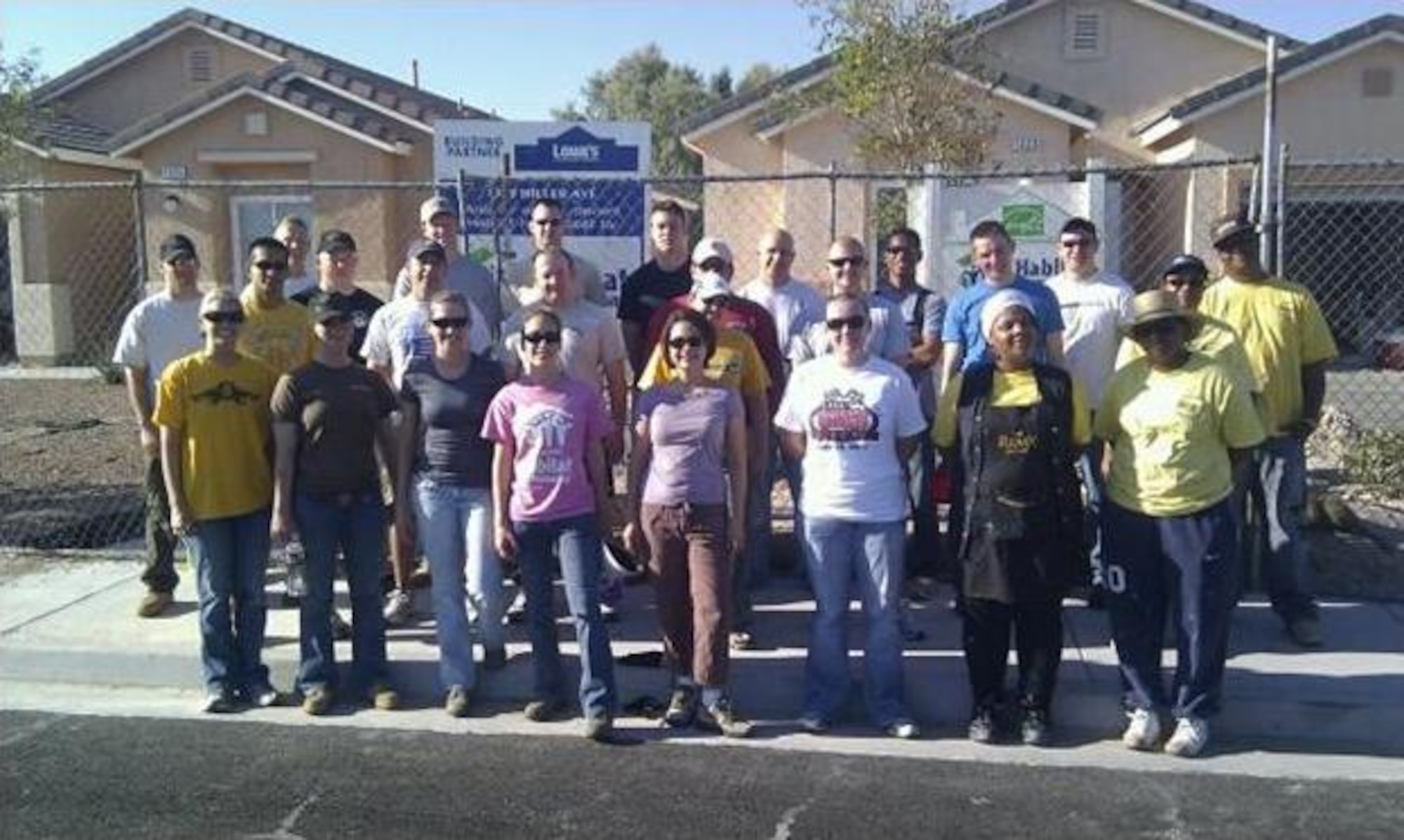Nellis Air Force Base company grade officers and four future Habitat for Humanity homeowners stand in front a Habitat for Humanity house July 23, 2011, in Las Vegas, Nev.  A total of 23 Nellis CGOs participated in this Habitat for Humanity project to help four future homeowners complete two houses.  (U.S. Air Force photo by Capt. Leticia Venegas/Released)