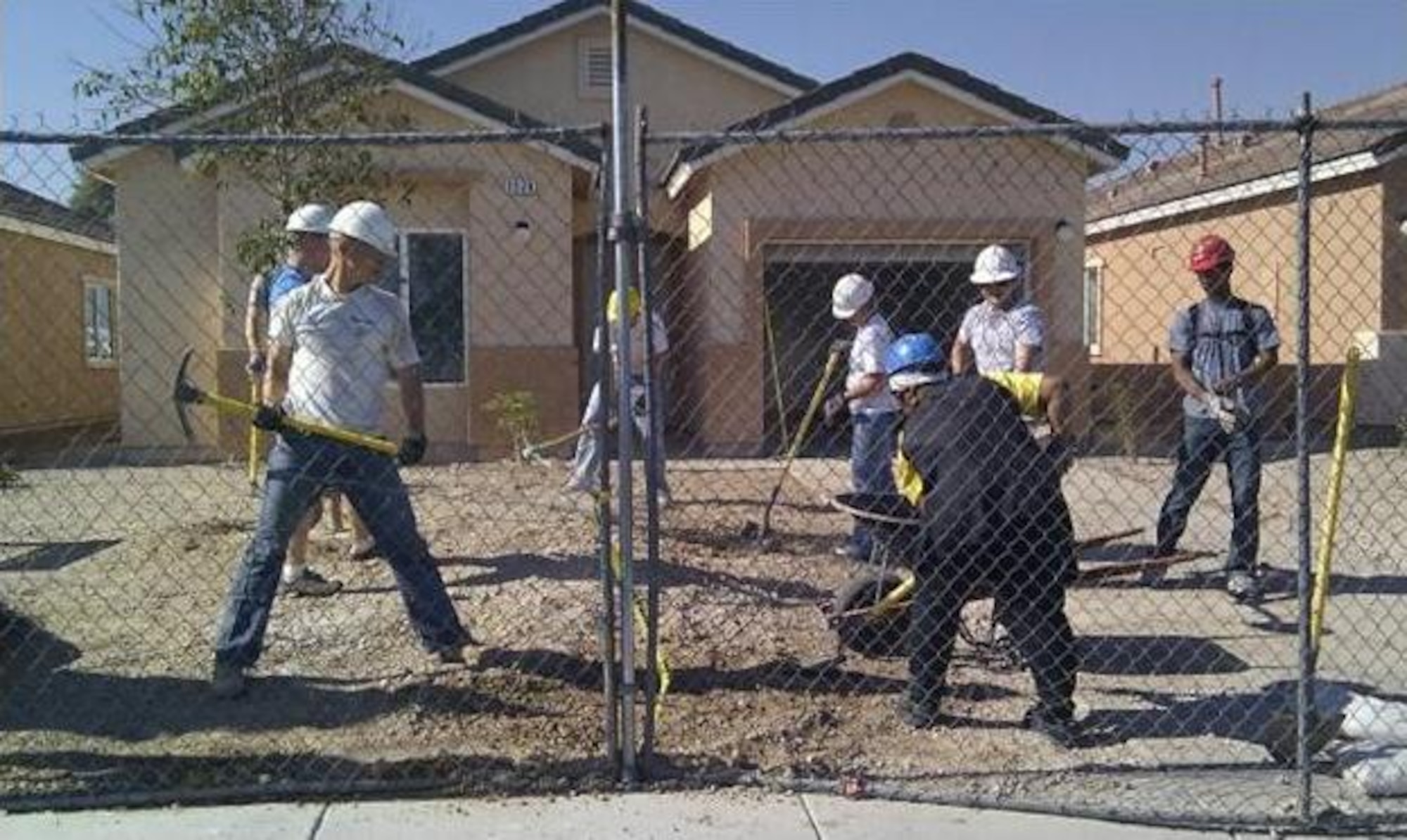 Nellis Air Force Base company grade officers and a future Habitat for Humanity homeowner work together to level a front yard in preparation for landscaping July 23, 2011, in Las Vegas, Nev.  A total of 23 Nellis CGOs participated in this Habitat for Humanity project to help four future homeowners complete two houses. (U.S. Air Force photo by Capt. Leticia Venegas/Released)