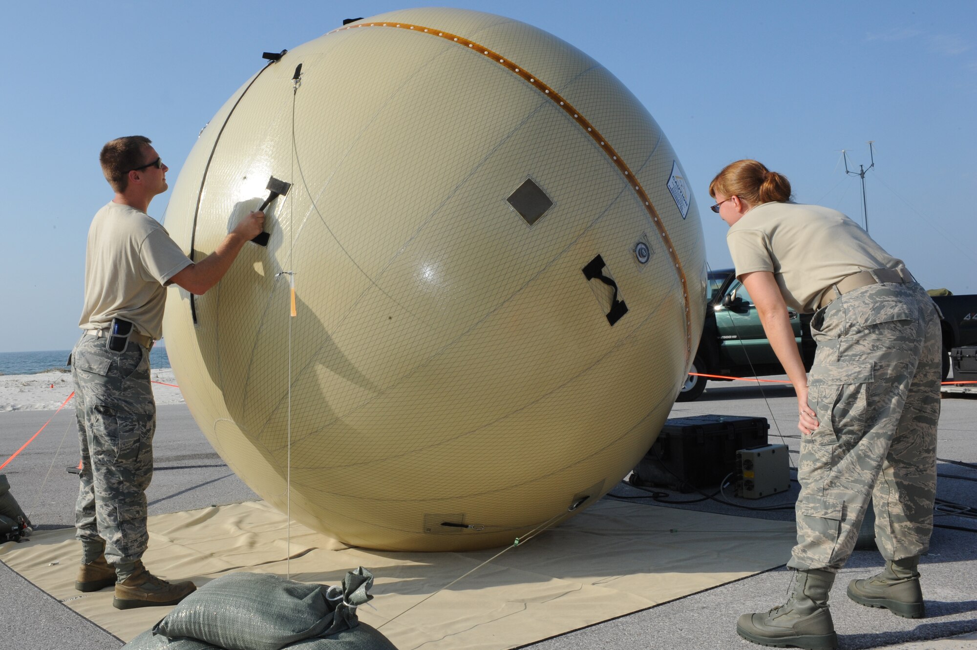 Staff Sgt. Shane Copenhaver, 1st Special Operations Communications Squadron, left, adjusts a ground antenna transmitter receiver as Tech. Sgt. Mindy Casto, 1st SOCS, looks on during Sand Dollar, a week-long, uninterrupted training exercise on Okaloosa Island, Fla., Aug. 11, 2011. The light-weight, transportable dish is able to withstand harsh winds and weather while relaying vital information back home. (U.S. Air Force photo by Senior Airman Eboni Reams)