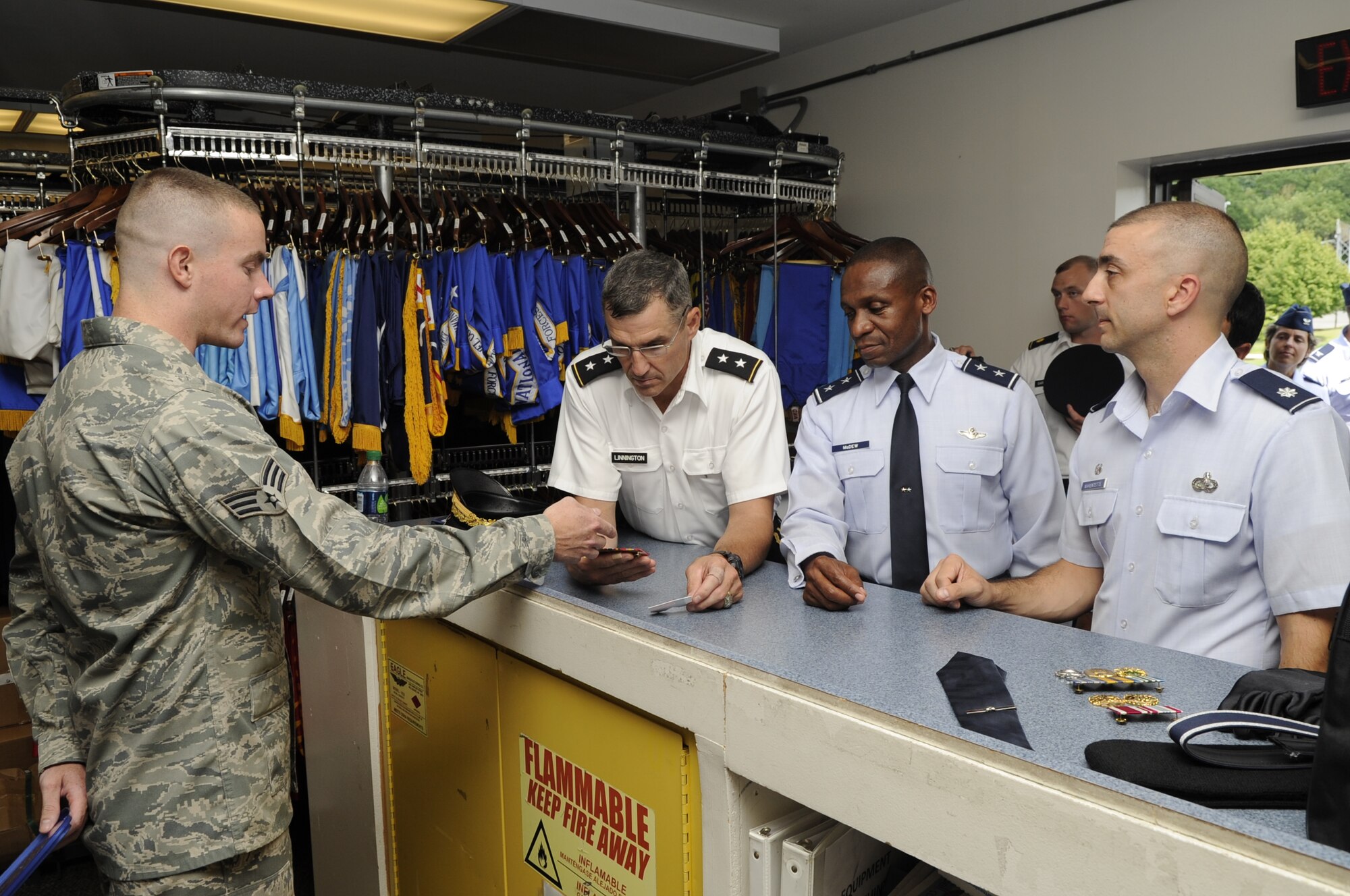 Senior Airmen Daniel Bennett, U.S. Air Force Honor Guard, briefs Army Maj. Gen. Michael Linnington, Joint Force Headquarters National Capital Region Military District of Washington commander, and Maj. Gen. Darren W. McDew, Air Force District of Washington commander, Aug. 8 on the Honor Guard's supply capabilities. In an effort to reduce costs, the Honor Guard produces and maintains their own program assets. (U.S. Air Force photo by Staff Sgt. Raymond Mills)