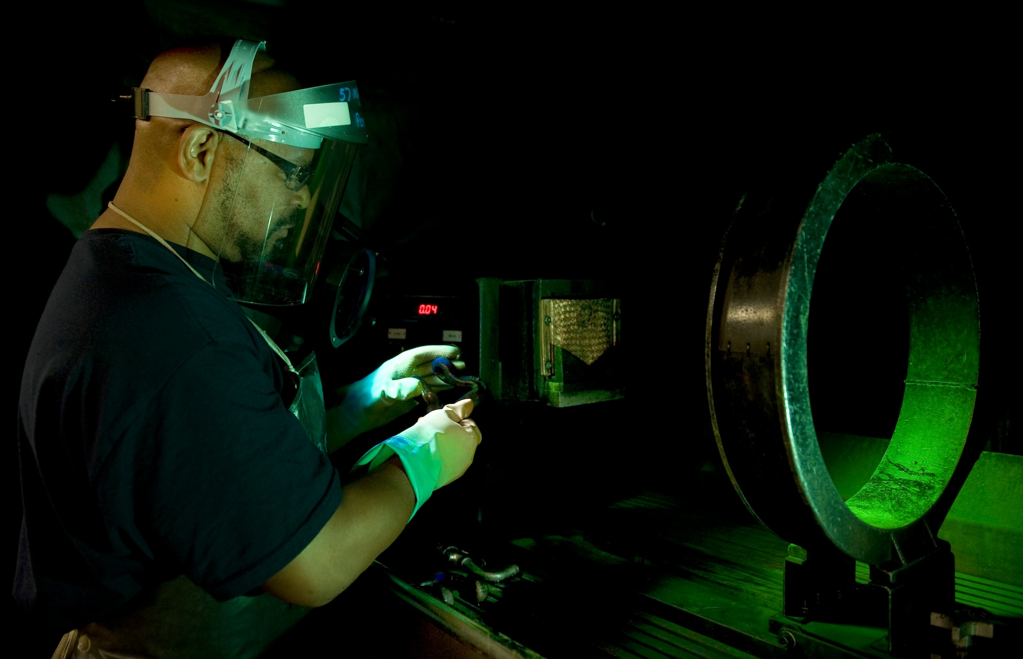Randy Davis, Computer Science Corporation aircraft mechanic 3 nondestructive inspection technician, performs a magnetic-particle inspection, Aug. 5, 2011, at Nellis Air Force Base, Nev.  Magnetic-particle inspections cause the discrepancies in aircraft parts to be visible. (U.S Air Force photo by Senior Airman Stephanie Rubi/Released)