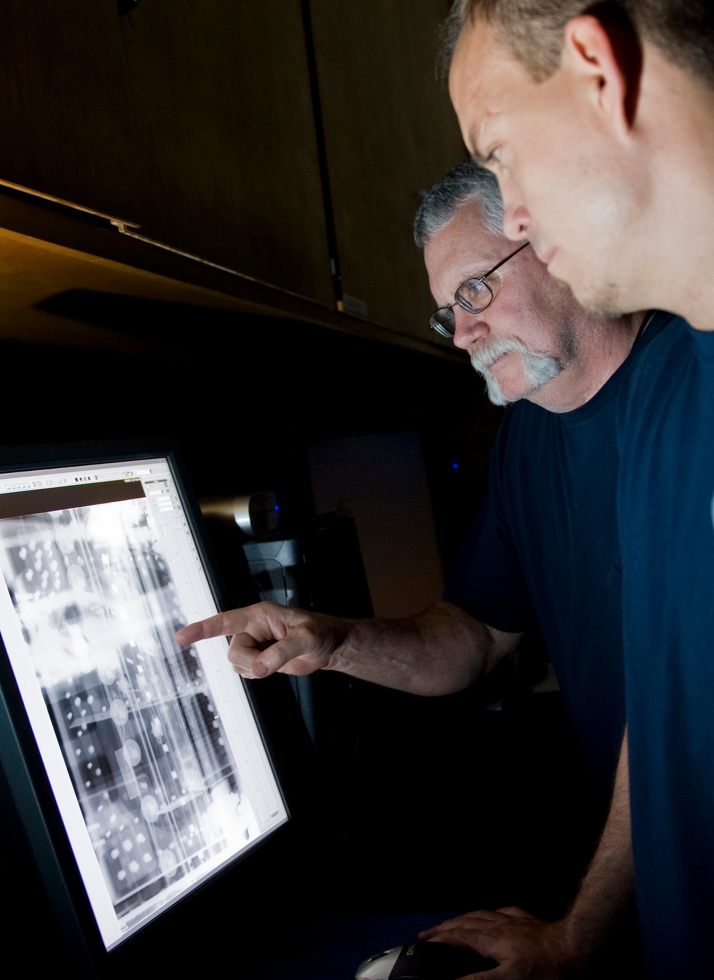 John Sanders, Computer Science Corporation aircraft mechanic 3 nondestructive inspection technician, and Joey Mabrey, Computer Science Cooperation aircraft mechanic 2 nondestructive inspection technician,  review a digital X-ray Aug. 5, 2011, at Nellis Air Force Base, Nev. X-ray's can be used to pinpoint damage in an aircraft and its structures.  (U.S Air Force photo by Senior Airman Stephanie Rubi/Released)