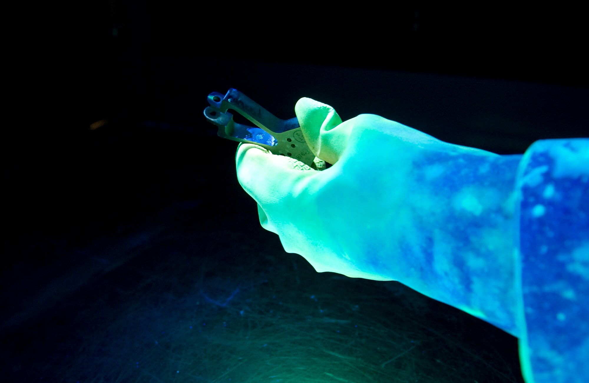 Randy Davis, Computer Science Corporation aircraft mechanic 3 nondestructive inspection technician, performs a florescent penetrant inspection, Aug. 2, 2011, at Nellis Air Force Base, Nev.  The use of florescent lights and solutions cause the discrepancies in aircraft parts to be visible. (U.S Air Force photo by Senior Airman Stephanie Rubi/Released)