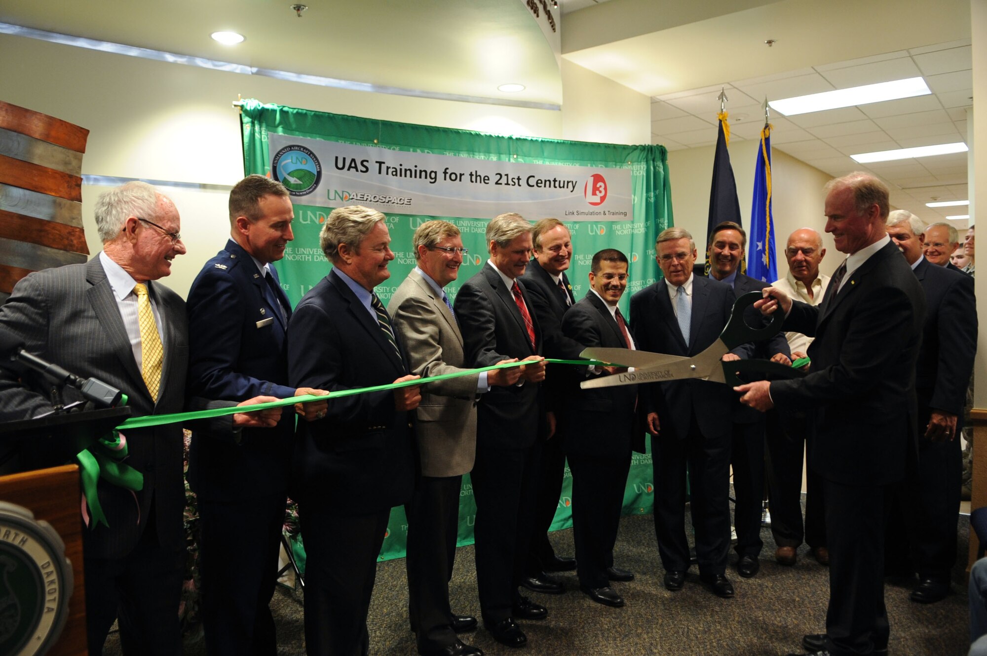 Col. Timothy E. Bush, 319th Air Base Wing commander, (second from left) and dignitaries from North Dakota watch as Robert O. Kelley,  University of North Dakota president, cuts the ribbon for the dedication of the UND Unmanned Aircraft Systems Training Facility on Grand Forks Air Force Base on Aug 10. The UND Unmanned Aircraft Systems Center of Excellence was established in 2006 and focuses on education and training for UAS integration into national airspace systems. (U.S. Air Force photo by Senior Airman Amanda N. Stencil)