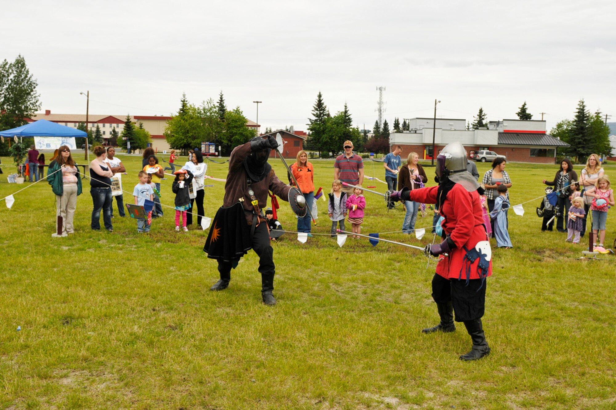 Knights of the Barony of Eskolya, Anchorage, duel in front of an audiance  during the  Joint Base Elmendorf-Richardson event "A Midsummer Knights Read" on the grounds of the base library. Activites included shield decorating, hat making and marshmello catapult contest. Members of the local Societ for Creative Anachronism were on hand with members dressed in the period and sword fighting in armour was displayed. (U.S. Air Force photo/Steven White)