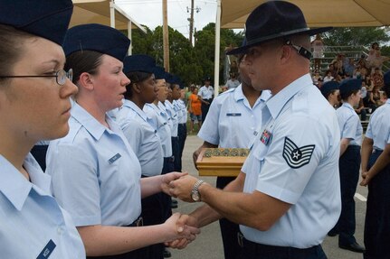Airman receives her Airman's Coin from her Military Training Instructor at the coin ceremony during graduation week events.  The coin signifies the transition from trainee to Airman.  (U.S. Air Force Photo/Melinda Mueller)