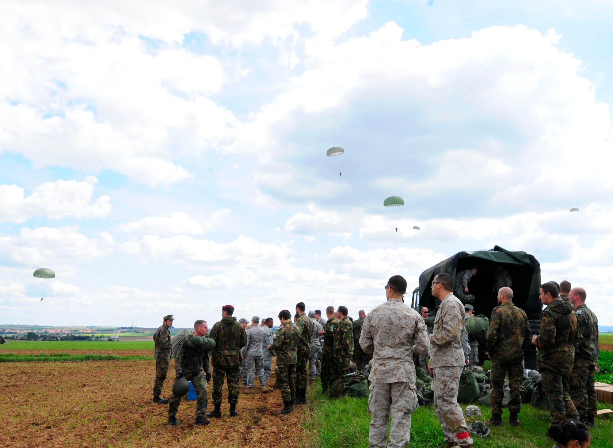 U.S. military members along with service members from five other NATO nations watch their comrades parachute over a drop zone during International Jump Week in Marnheim, Germany, Aug. 10, 2011. Six NATO countries participated in the annual event to support one of U.S. Air Forces in Europe's top priorities; building partnership capacity. More than 200 U.S. and NATO jumpers participated in the week-long training. (U.S. Air Force photo by Airman 1st Class Kendra Alba)