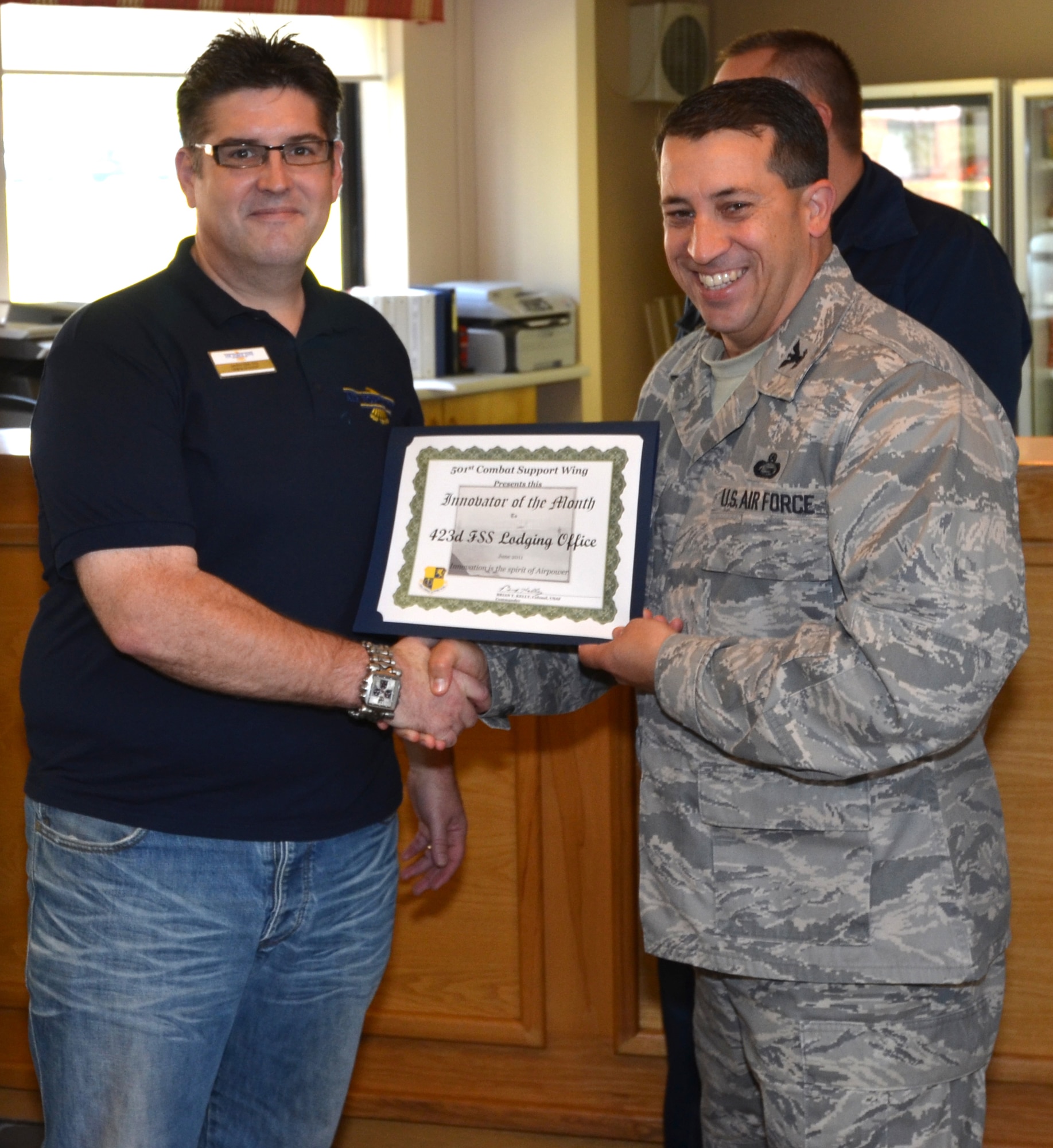 RAF ALCONBURY, United Kingdom - Col. Brian Kelly, 501st Combat Support Wing commander, presents the Innovator of the Month award to Geoffrey Clark, 423rd Force Support Squadron Lodging Office. Micah Gathercoal, Pablo Arrieta and Steven Henson were part of the team that earned the June Innovator of the Month award. (U.S. Air Force photo by 1st Lt. Brian Maguire)