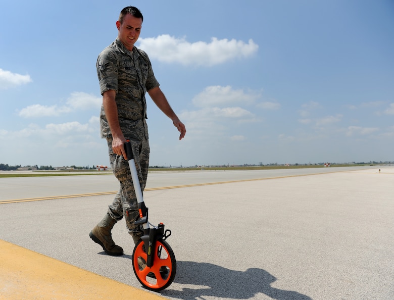 Airman 1st Class Phillip Rinde, 39th Operations Squadron airfield management apprentice, measures the width of a taxiway using a measuring-wheel gauge Aug. 10, 2011, at Incirlik Air Base, Turkey. Airfield management measures the taxiways to make sure they are wide enough for aircraft and to ensure lines are the correct size and distance from each other. (U.S. Air Force photo by Senior Airman Anthony Sanchelli/Released)