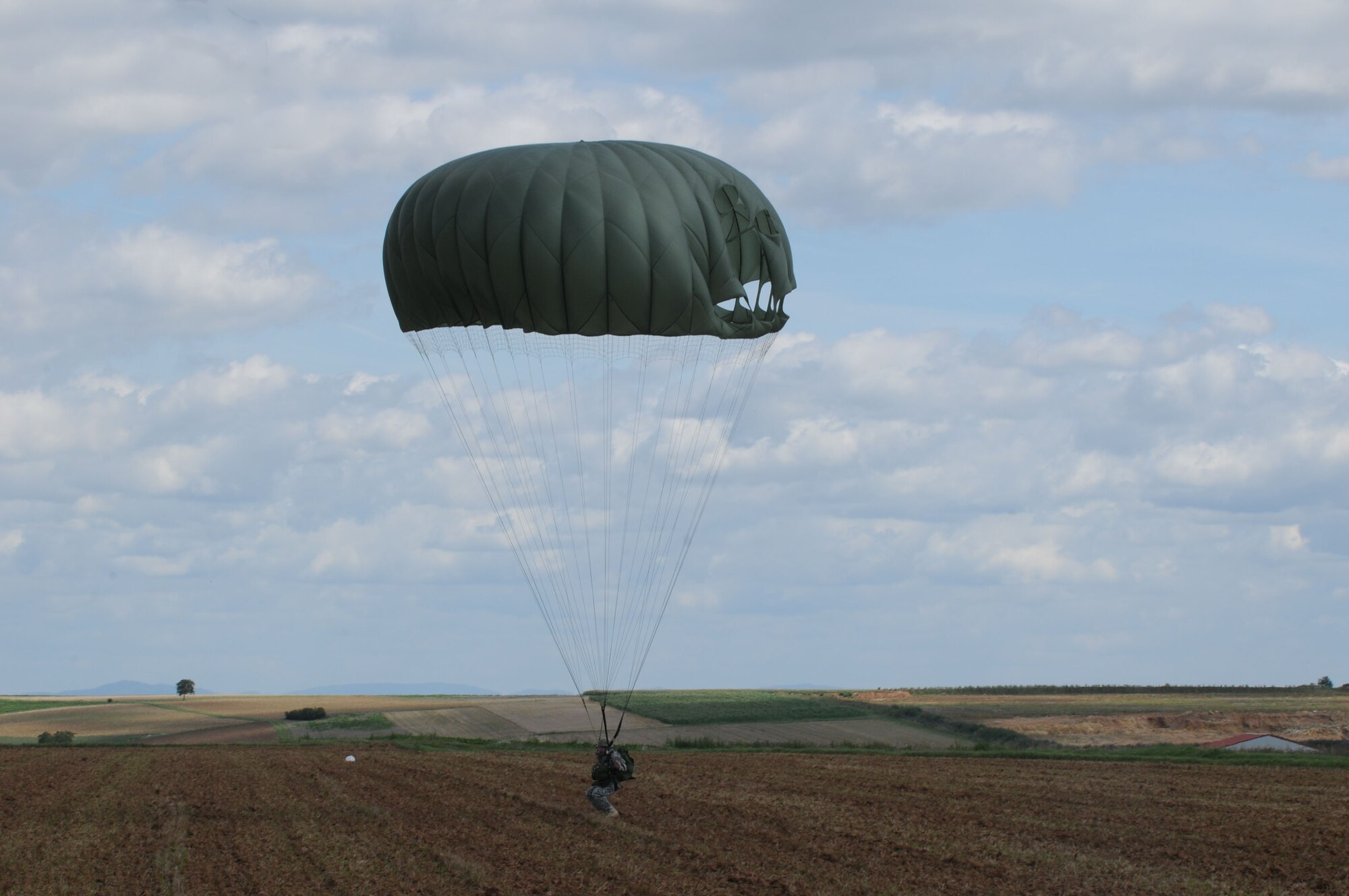 A U.S. military member lands in the designated drop zone during International Jump Week in Marnheim, Germany, Aug. 10, 2011. Six NATO countries participated in the annual event to support one of U.S. Air Forces in Europe's top priorities; building partnership capacity. More than 200 U.S. and NATO jumpers participated in the week-long training. (U.S. Air Force photo by Airman 1st Class Kendra Alba)