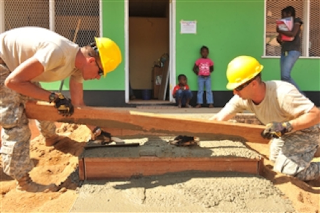 U.S. Army Sgt. Jerome Bernard (left) and Spc. Bob O'Grady, both with the 155th Engineering Company of the South Dakota Army National Guard, level concrete during the remodeling of the Pater van der Pluym School in Brownsweg, Suriname, during New Horizons Suriname 2011 on Aug. 8, 2011.  New Horizons Suriname is a U.S. Southern Command-directed joint humanitarian and civic assistance mission deploying U.S. military engineers, veterinarians, medics and other professions to Suriname for training, construction projects and to provide humanitarian and medical services.  
