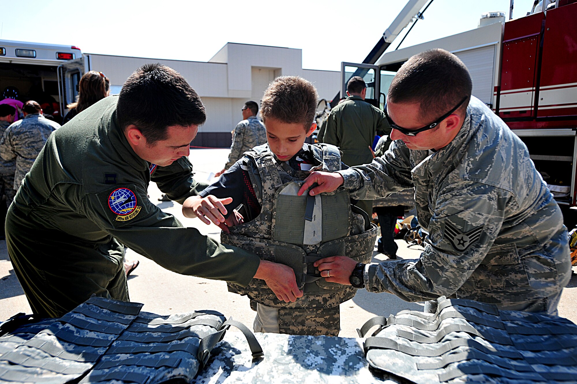 Capt. Brandon Strong, 349th Air Refueling Squadron chief of safety, and Staff Sgt. Matthew Altheim, 22nd Security Forces NCOIC of corrections, helps Xavier, 8 years old, put on a flack vest during the”Big for a Day” event Aug. 12, 2011, at McConnell Air Force Base, Kan. McConnell has partnered with the Big Brothers Big Sisters for more than 25 years.  Each year, the event offers new displays to help the children understand what Airmen do on a daily basis. (U.S. Air Force photo/ Senior Airman Courtney Witt)