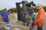 (left to right) Tony Lara, Rene Hernandez and Tracy Meek, recycling center technicians, move a bale of cardboard from the baler to a holding area at the center Aug. 12. (U.S. Air Force photo/Rich McFadden) (released)