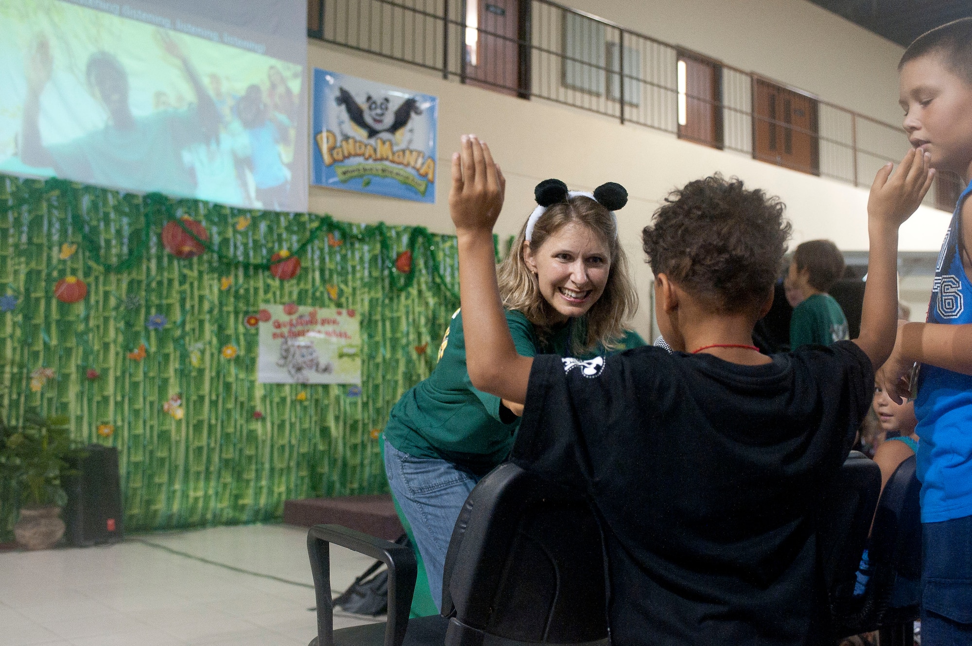 Tina Olson, PandaMania Vacation Bible School volunteer, passes a microphone to a child to sing at VBS Aug. 11, 2011, at Incirlik Air Base, Turkey. VBS was held Aug. 8-12 and is an annual event that provides a fun way for children to reinforce their religious teachings. (U.S. Air Force photo by Airman 1st Class Clayton Lenhardt/Released)