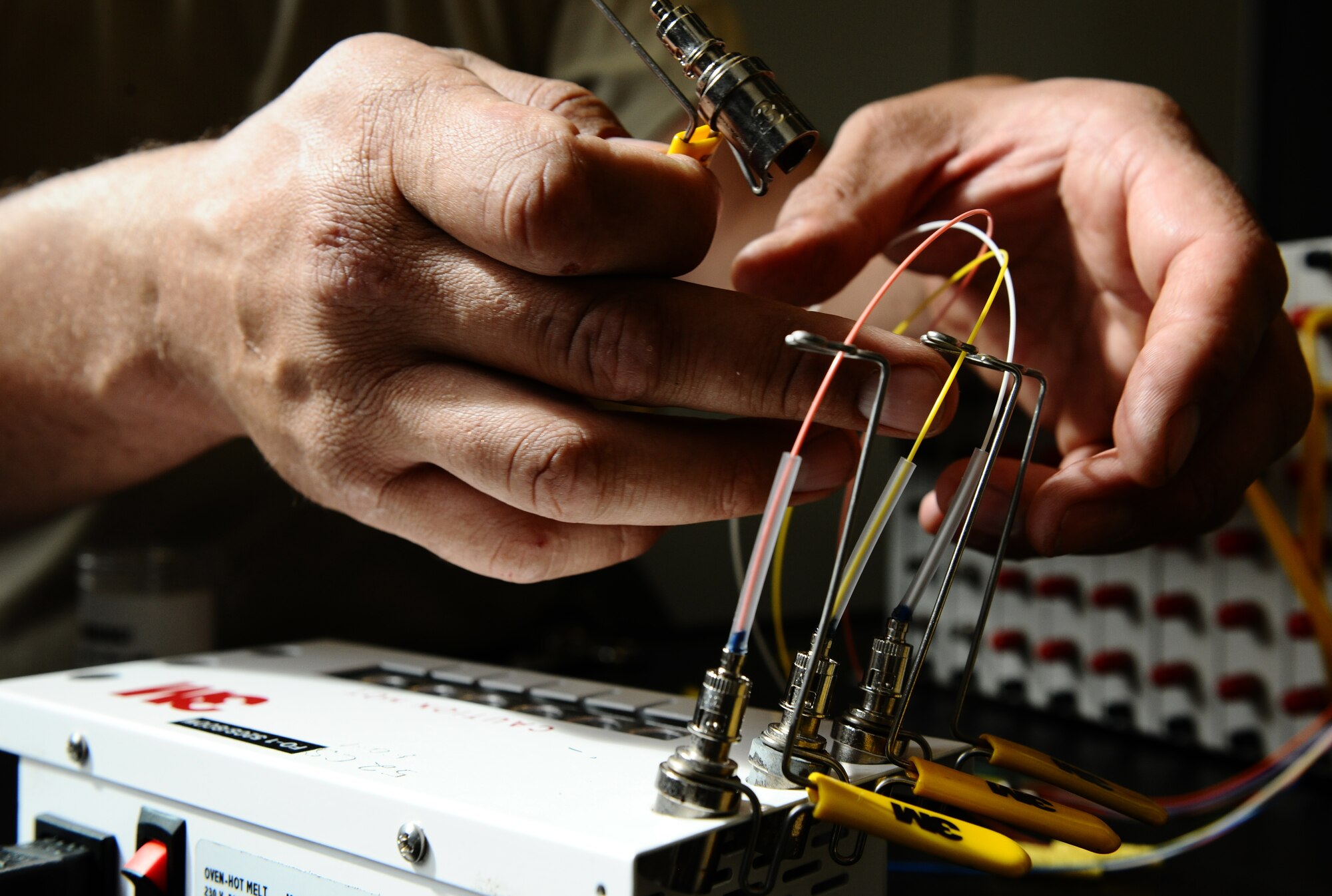 BITBURG ANNEX, Germany -- Tech. Sgt. Benjamin Reid, 52nd Communications Squadron cable maintenance NCO in charge, hot melts optical fiber cable to straight tip connectors, which connect the cable to the back of a patch panel here Aug. 11. The 52nd CS worked with local contractors to repair a damaged optical fiber line outside Bitburg Annex, which knocked out all the annex’s DSN telephone lines. The cable maintenance technicians repaired the lines after they were inadvertently cut off base Aug. 9. (U.S. Air Force photo/Staff Sgt. Nathanael Callon)