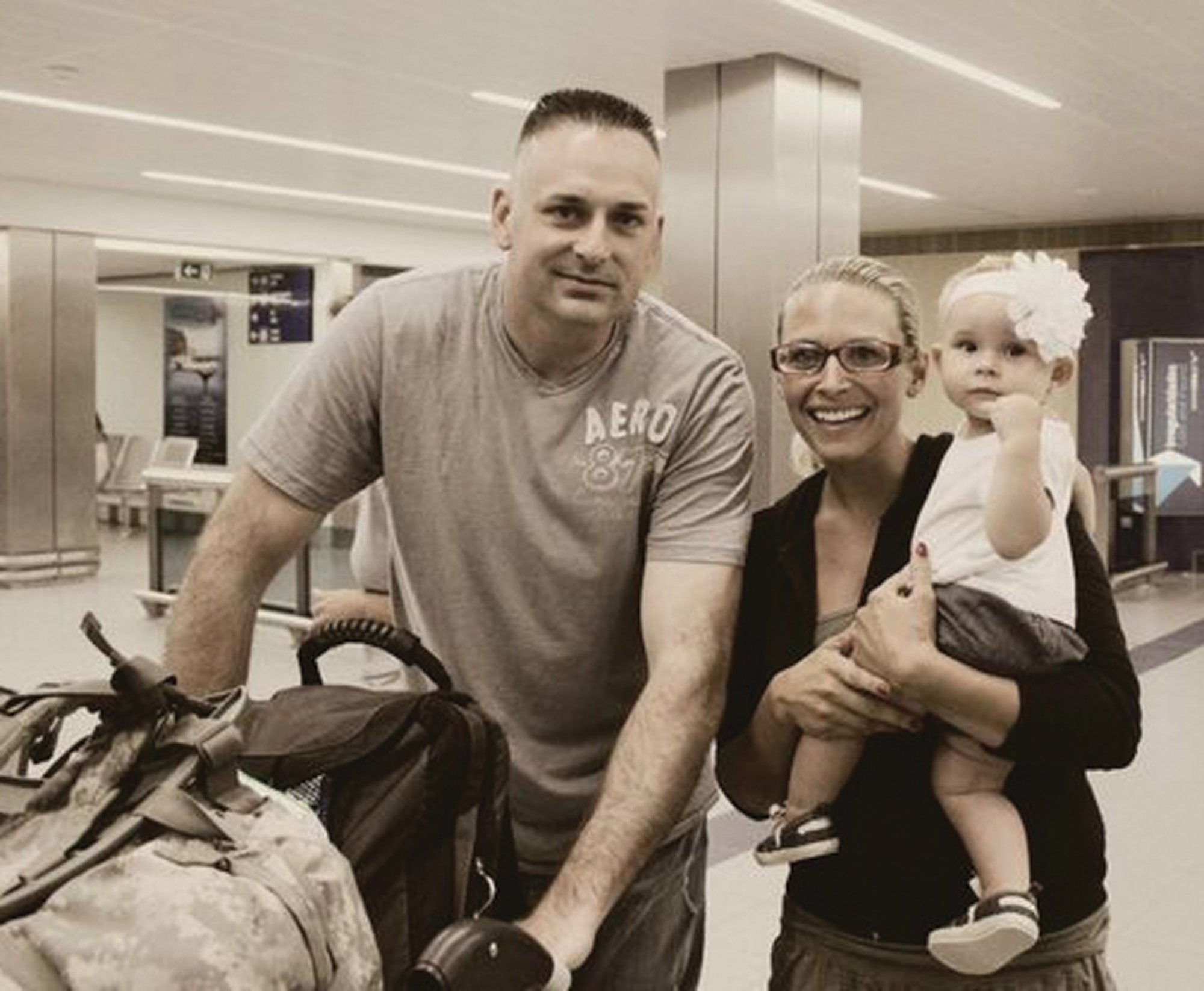 Master Sgt. Nikki Drago, 65th Security Forces Squadron, his wife Melissa Drago, and their daughter, Carmen, pose at the Lajes Field Terminal after Drago surprised his family by returning early from his deployment Aug. 4.  Melissa Drago is the 65th Security Forces Key Spouse, and is glad her husband is back home safe. (Courtesy photo)