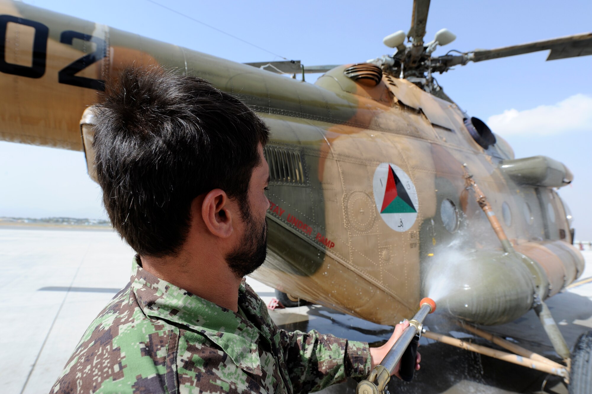A member of the Afghan Air Force sprays down the side of an AAF Mi-17 helicopter at Kabul International Airport, Kabul Afghanistan, August 11, 2011. Coalition Airmen here work daily to set the conditions for a professional, fully independent and operationally-capable AAF. (U.S. Air Force photo by Staff Sergeant Matthew Smith)