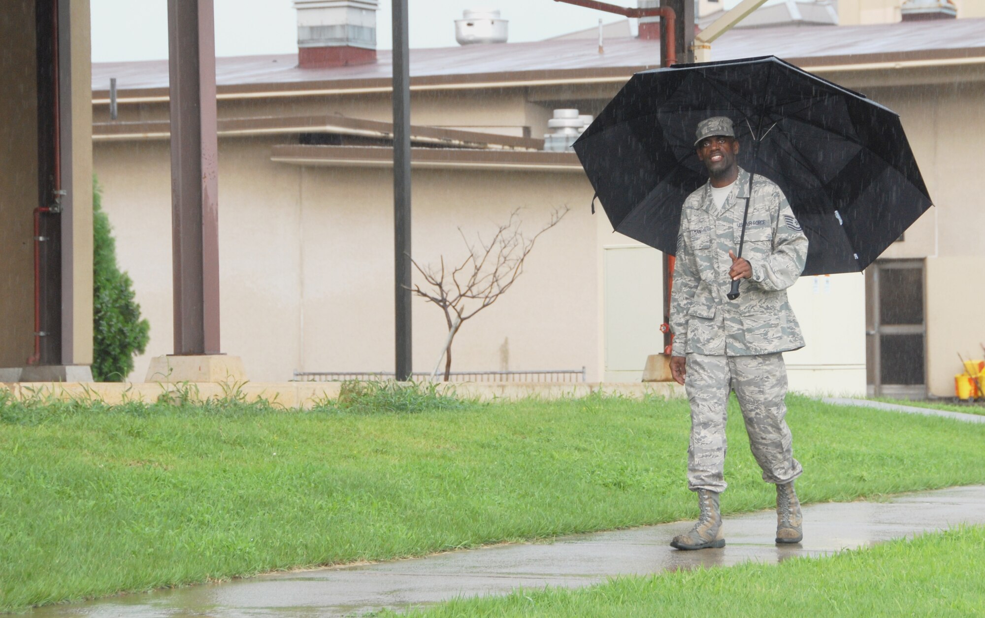 Tech. Sgt. Amos Pittman, 8th Civil Engineer Squadron housing flight, walks through the rain with his umbrella during an afternoon shower at Kunsan Air Base, Republic of Korea, Aug. 12. The 8th Civil Engineer Squadron requires weather reports to accomplish day to day tasks, as well as to stay ahead of flooding during the summer and snowstorms in the winter.  (U.S. Air Force photo/Capt. Omar Villarreal) 