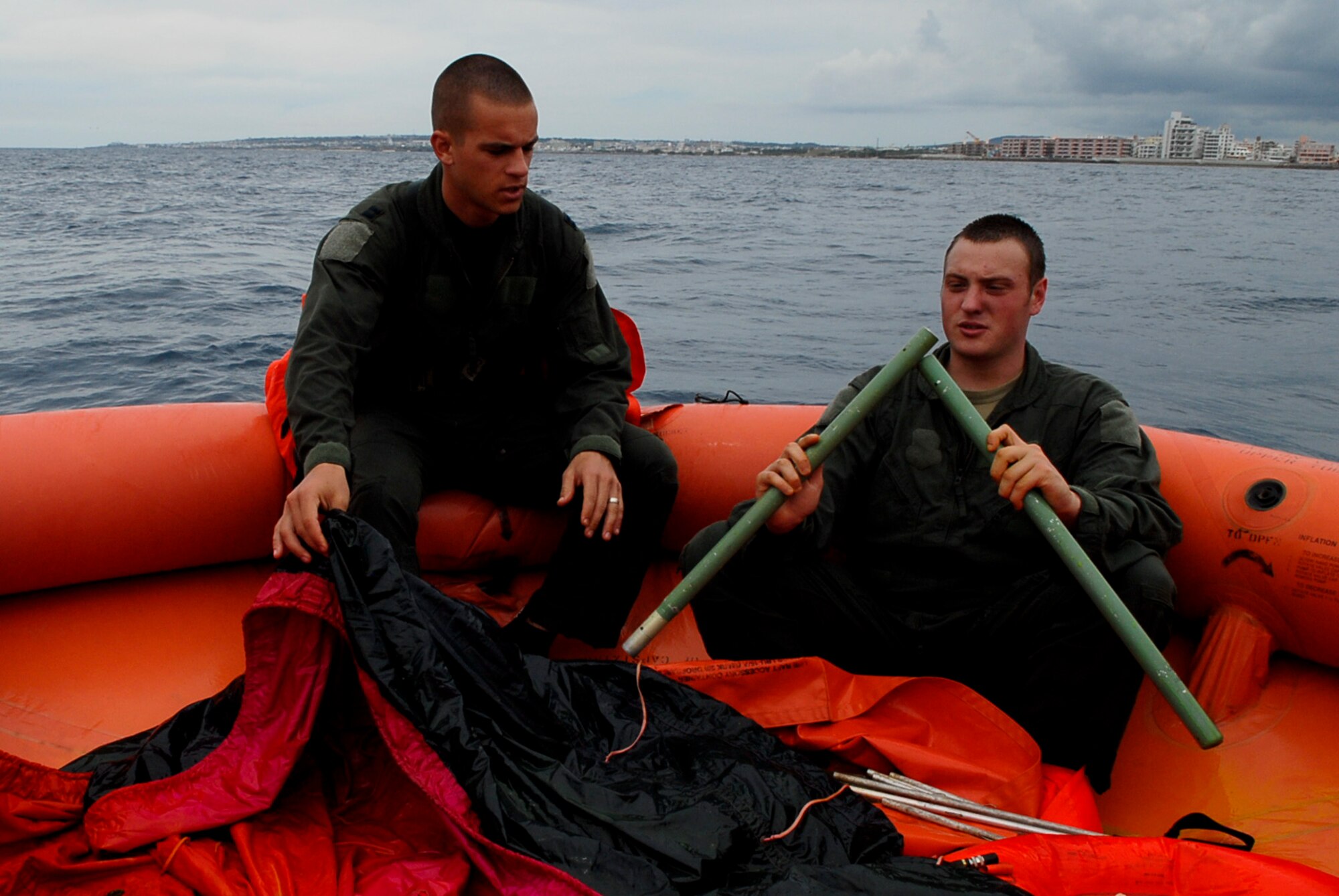 Capt. Chris Moran, 909th Air Refueling Squadron KC-135 pilot, and Senior Airman Dan Childress, 909th Air Refueling Squadron KC-135 boom operator, work to put together poles to construct a canopy out of an aircraft survival kit?s tarp while in a life raft during a water survival refresher course Aug. 11 at the Kadena Marina in Okinawa, Japan. This survival course reviews health risks, being stranded in a combat area, rescue procedures and the items in the survival kit. (U.S. Air Force photo/ Airman 1st Class Tara A. Williamson)