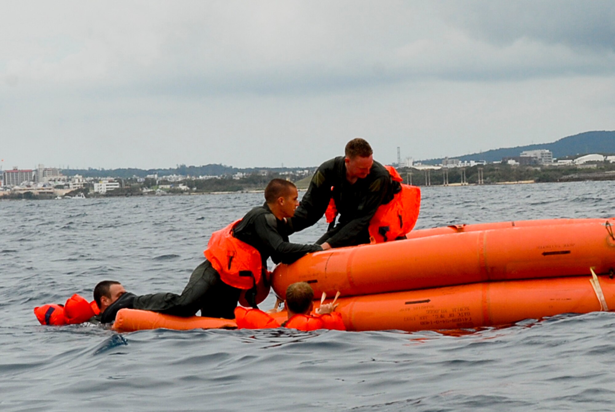 Capt. Travis Epp, 909th Air Refueling Squadron KC-135 pilot, assists fellow aircrew members into a life raft during a water survival refresher course Aug. 11 at the Kadena Marina in Okinawa, Japan. The aircrew members train with a survival kit similar to those located on their aircraft. (U.S. Air Force photo/ Airman 1st Class Tara A. Williamson)
