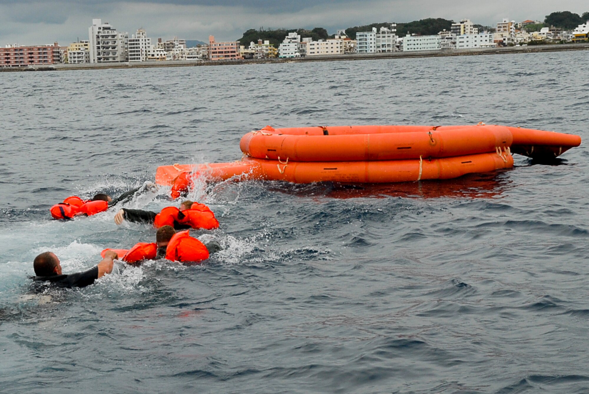 Four aircrew members and Staff Sgt. William Lambert, 18th Operations Group Survival, Evasion, Resistance, and Escape specialist, swim to a life raft during a water survival refresher course Aug. 11 at the Kadena Marina in Okinawa, Japan. This survival course is required every three years for aircrew members to familiarize themselves with the equipment and skills needed if they find themselves making a water landing. (U.S. Air Force photo/ Airman 1st Class Tara A. Williamson)