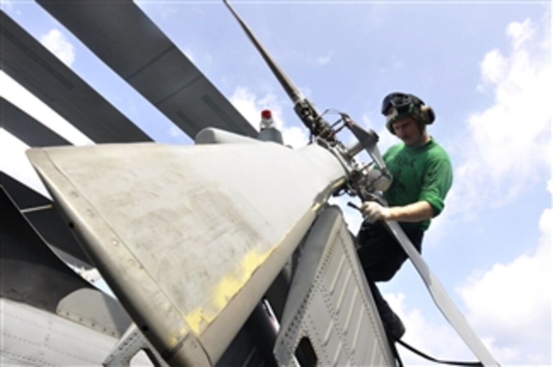 U.S. Navy Petty Officer 2nd Class Branden Rucker performs maintenance to control corrosion on the tail rotor of an SH-60F Seahawk helicopter assigned to Helicopter Anti-Submarine Squadron 4 aboard the aircraft carrier USS Ronald Reagan (CVN 76) in the South China Sea on Aug. 9, 2011.  The Ronald Reagan is underway in the U.S. 7th Fleet area of responsibility.  