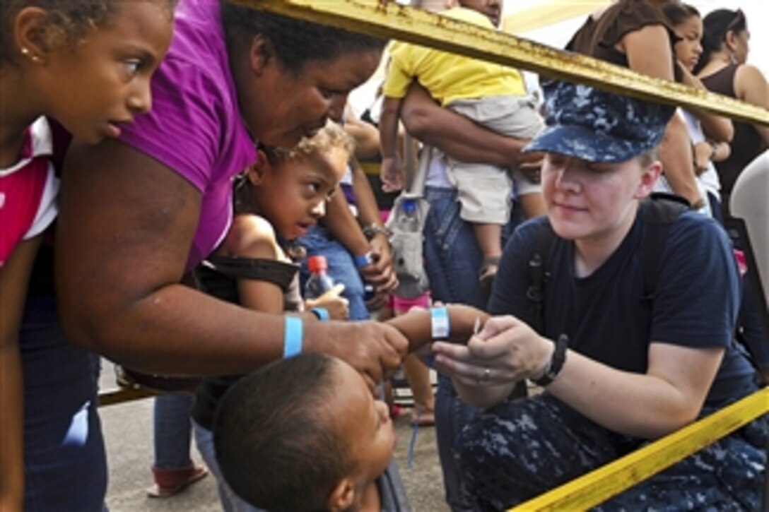 U.S. Navy Petty Officer 2nd Class Tanya Carr puts a band on a patient's wrist before entering the Barranca Municipal Gym medical site during Continuing Promise 2011 in Barranca, Costa Rica, on Aug. 5, 2011.  