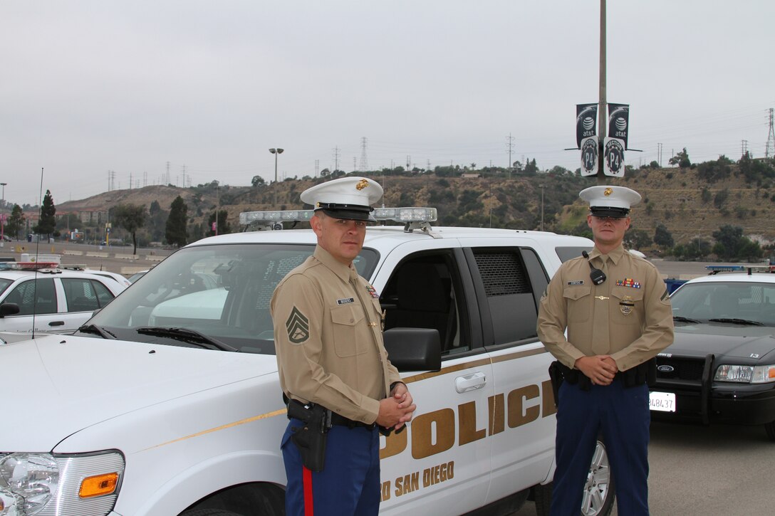 Staff Sgt. Jason Biggers (left) military policeman, Headquarters Company, Headquarters and Service Battalion and Lance Cpl. Daniel Contois (right) military policeman, Headquarters Co., H & S Bn., stand in front of a Marine Corps Recruit Depot San Diego K-9 vehicle before the funeral procession for Police Officer Jeremy Henwood Aug. 12, at Qualcomm Stadium.