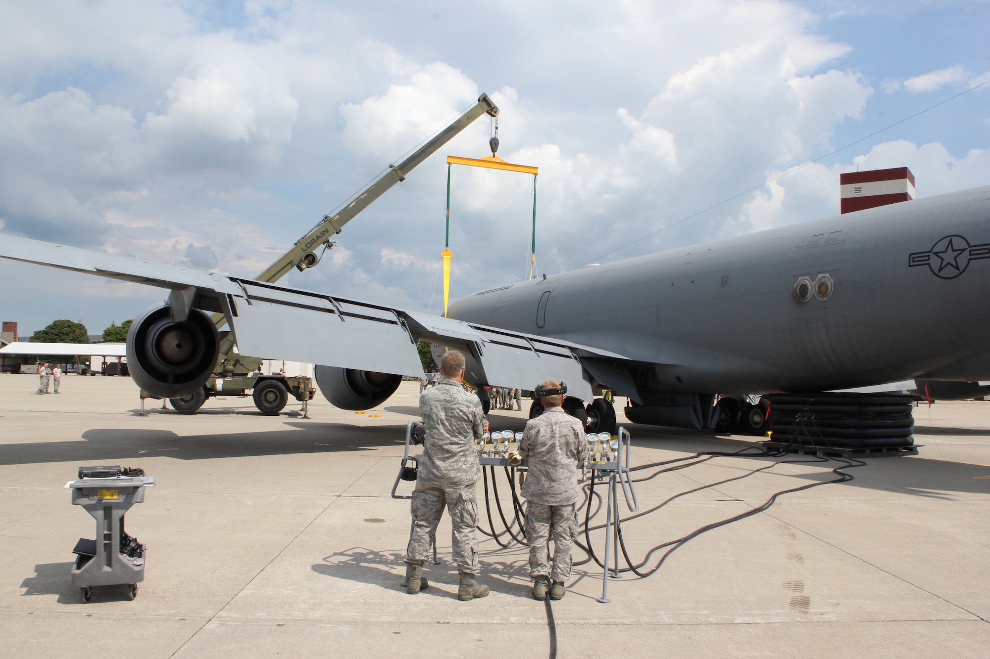 Two Airmen monitor an air pressure regulator as a crane prepares to lift the nose of a KC-135 Stratotanker during an exercise at Selfridge Air National Guard Base, Mich., Aug. 13, 2011. The 191st Maintenance Squadron performed an exercise in which they simulated a KC-135 Stratotanker had damaged nose gear and a crane was needed to move the aircraft to a safe location for repair. At the tail of the aircraft a series of inflated air bladders were used to help support the aircraft during the operation. (USAF photo by TSgt. Dan Heaton)