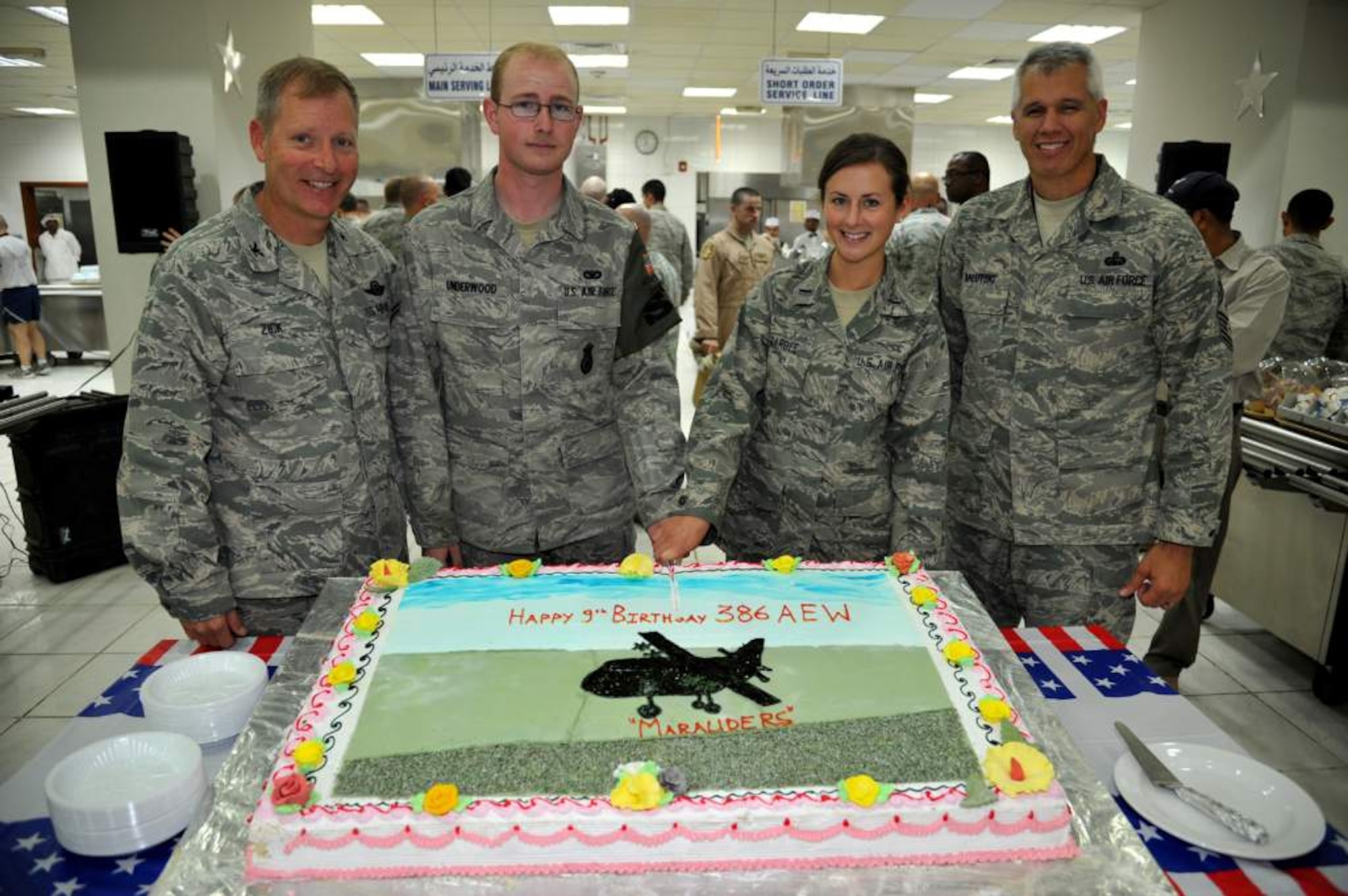 Col Michael Zick, 386th AEW commander (left) and Chief Master Sgt Mitchell Balutski, 386th command chief (right) are on hand as Airman First Class Cody Underwood (center left) and First Lieutenant Jessica Barbee (center right), the youngest enlisted and officer, make the celebratory cut in the cake to commemorate the ninth birthday of the wing.  (U.S. Air Force photo by MSgt Carlotta Holley)