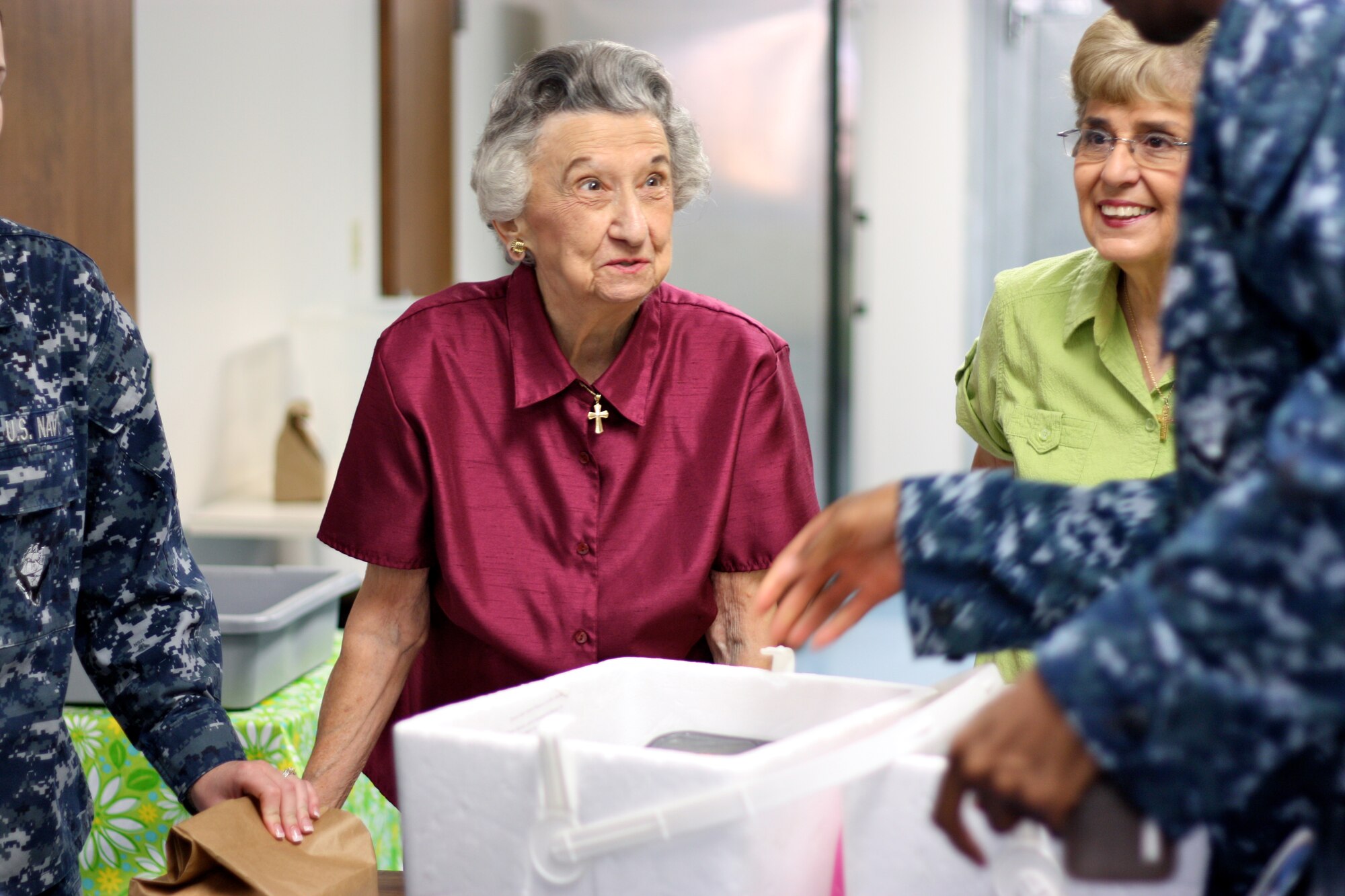 SAN ANGELO, Texas -- Meals for the Elderly volunteers Jenny Sakellariou (left) and Sylvia Lindenschmidt (right) helps a group of Navy volunteers pack meals for delivery Aug. 12.  (Courtesy photo/Whitney Haskell)