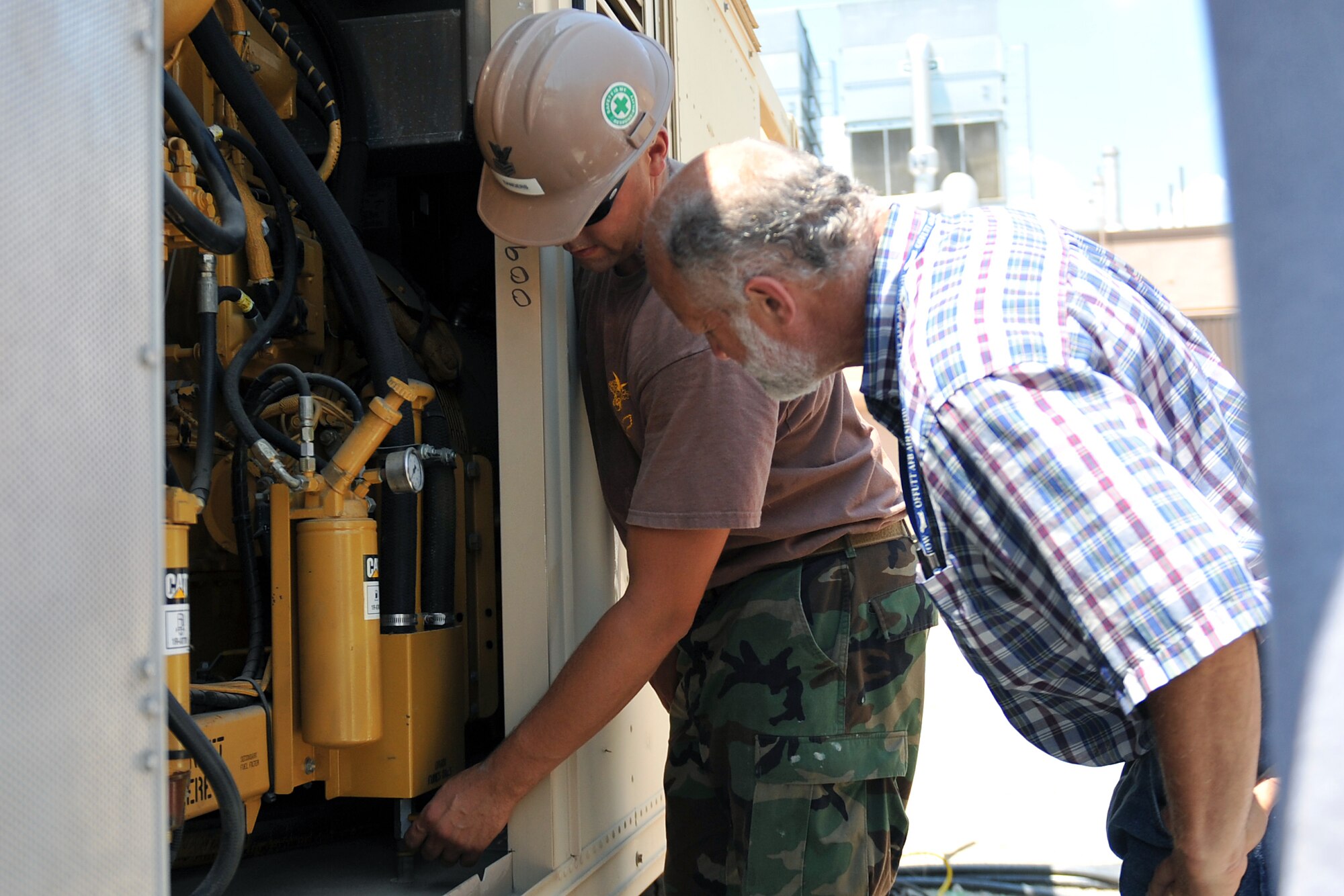 Petty Officer 1st Class Eric Sanders, a utilitiesman with a Mobile Utilities Support Equipment team from Port Hueneme, Calif., shows Steve Soleta, power production technician with the 55th Civil Engineer Squadron, how to operate one of their generators July 19 at Offutt Air Force Base, Neb. The MUSE team was here from July 18-27 to install a 3.2 megawatt power plant in conjunction with a 5000 KVA substation. (Air Force photo by Jeff Gates)